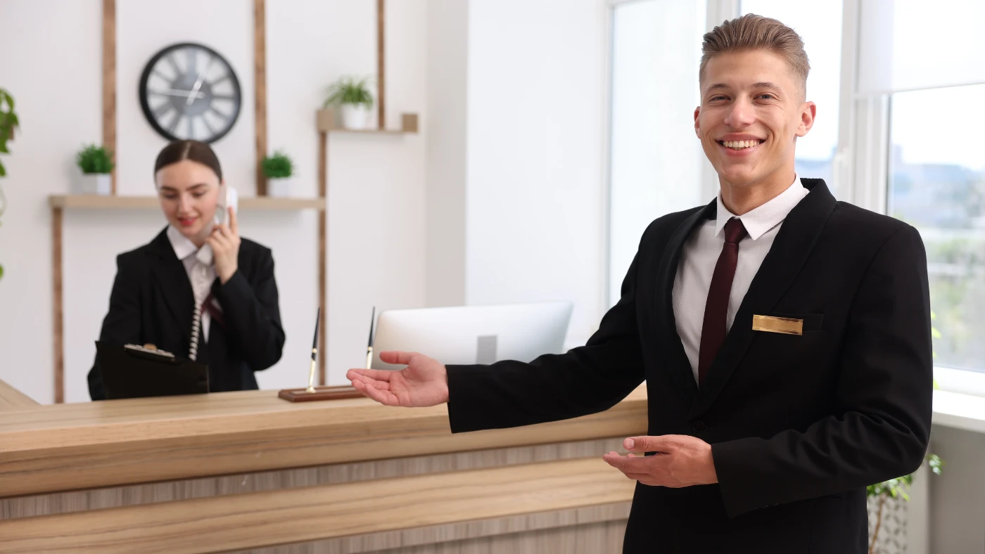 Professional villa hospitality staff welcoming guests at a reception desk.