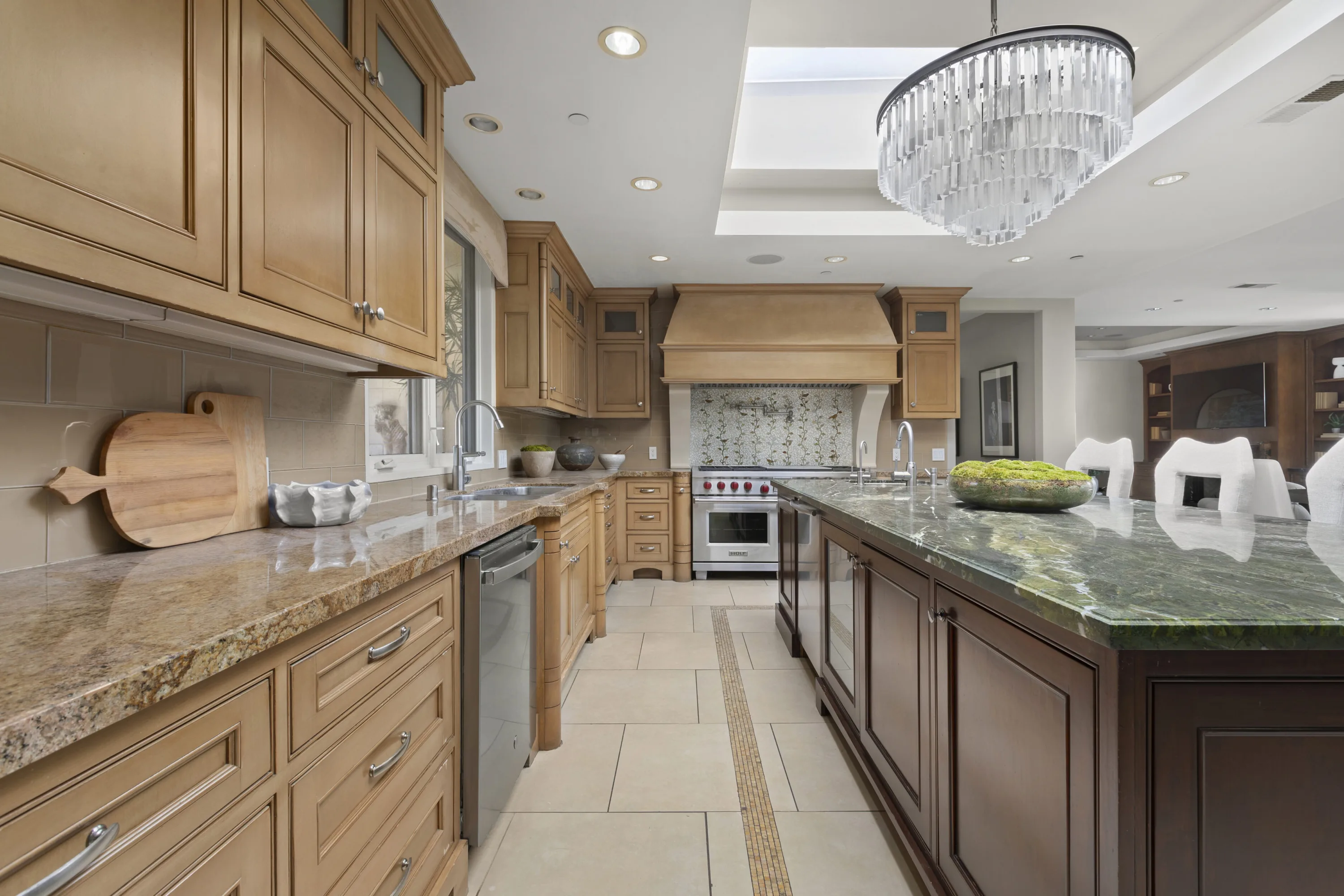 Prep run of the kitchen: granite counters, professional range under a hooded alcove, long island in green marble