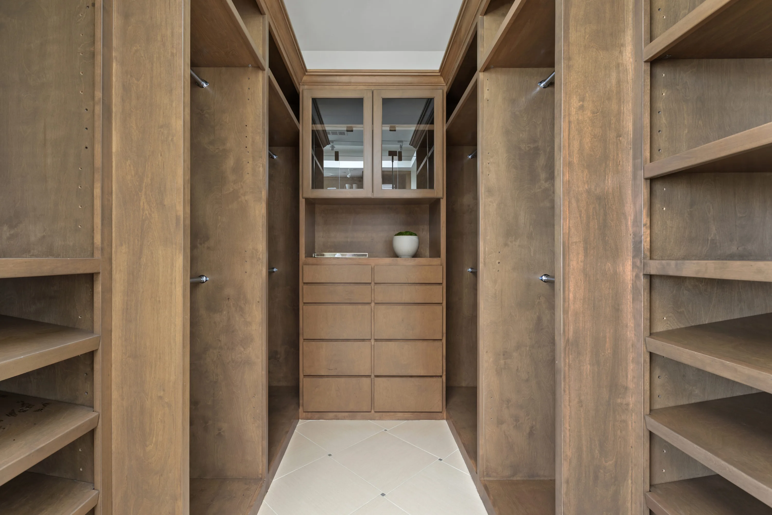 Fitted walk-in wardrobe lined with open hanging bays, shoe shelving and a bank of drawers