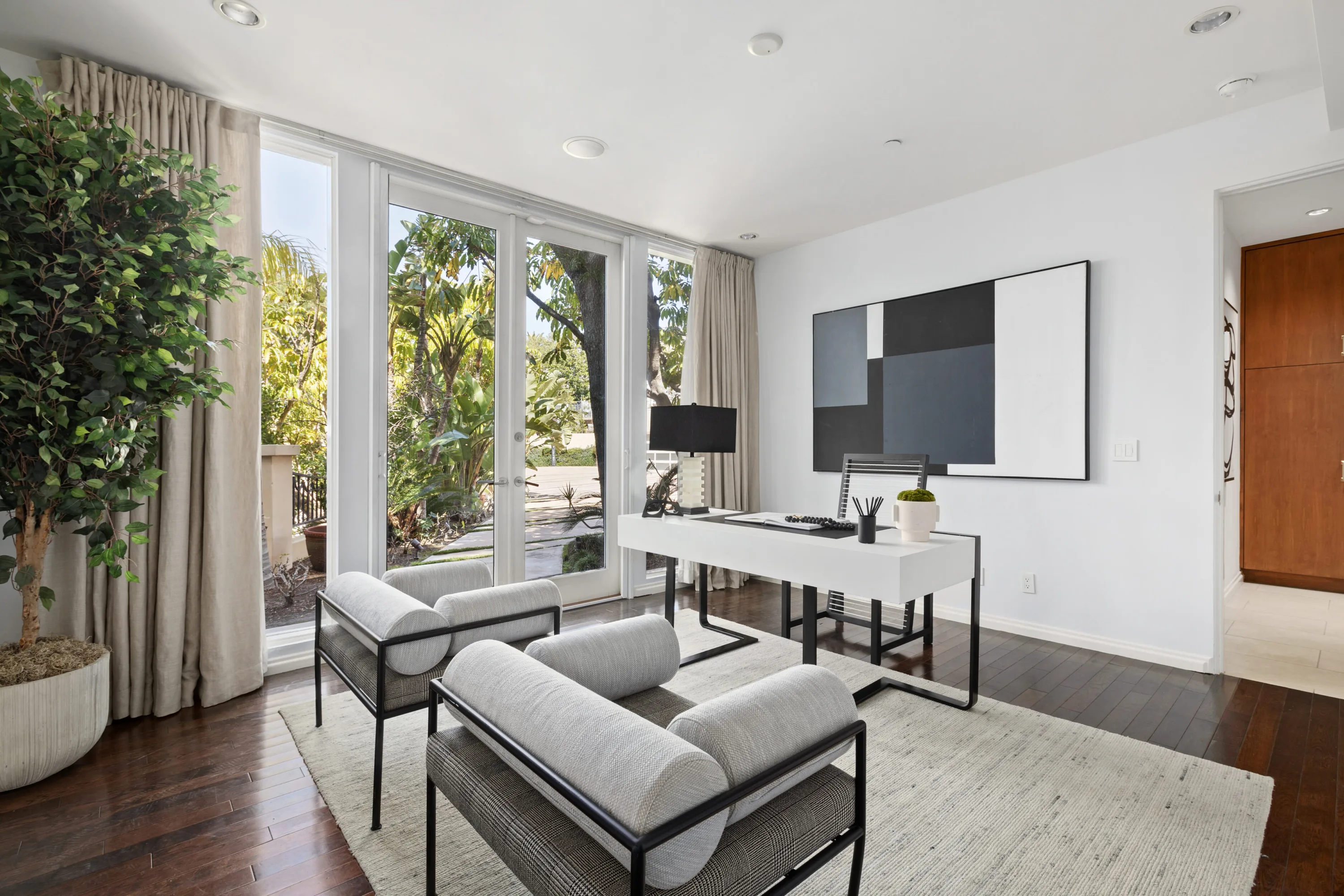 Study with white desk, graphic grey artwork and garden doors onto a planted side terrace