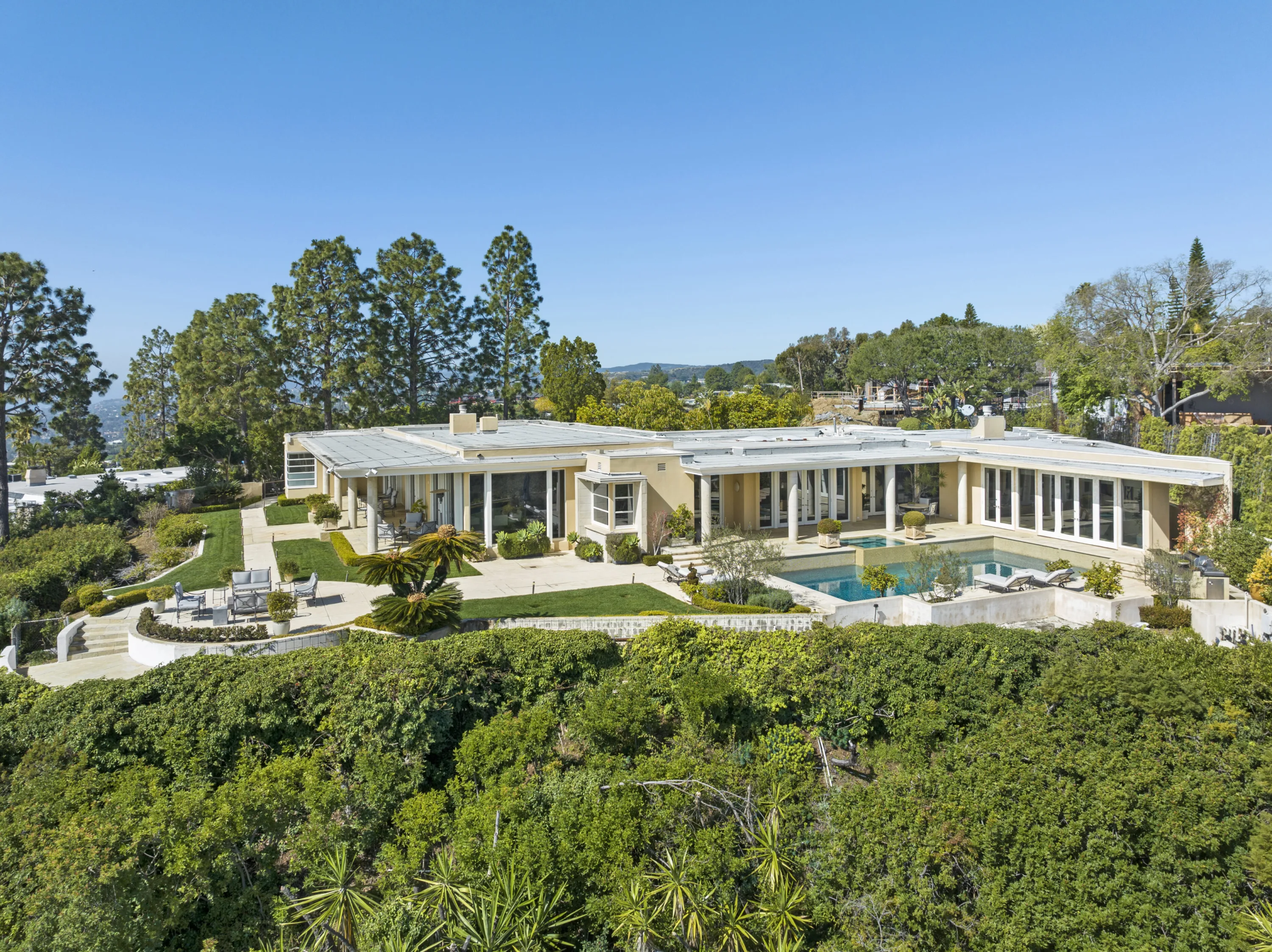 Aerial of the single-storey house wrapping lawns and pool on its Trousdale Estates ridge lot
