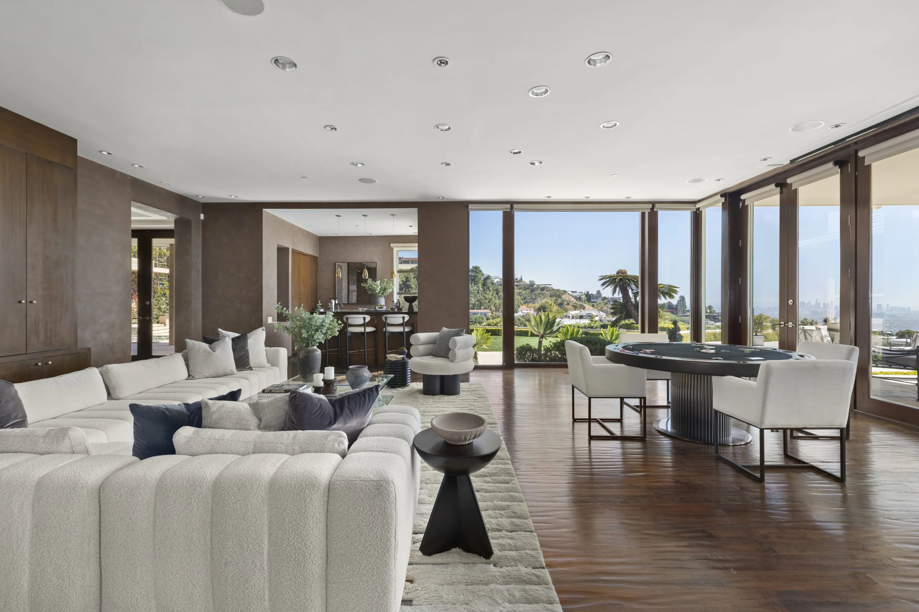 Games corner with felt poker table beside the lounge seating, walls of glass onto the lawn and ridgeline