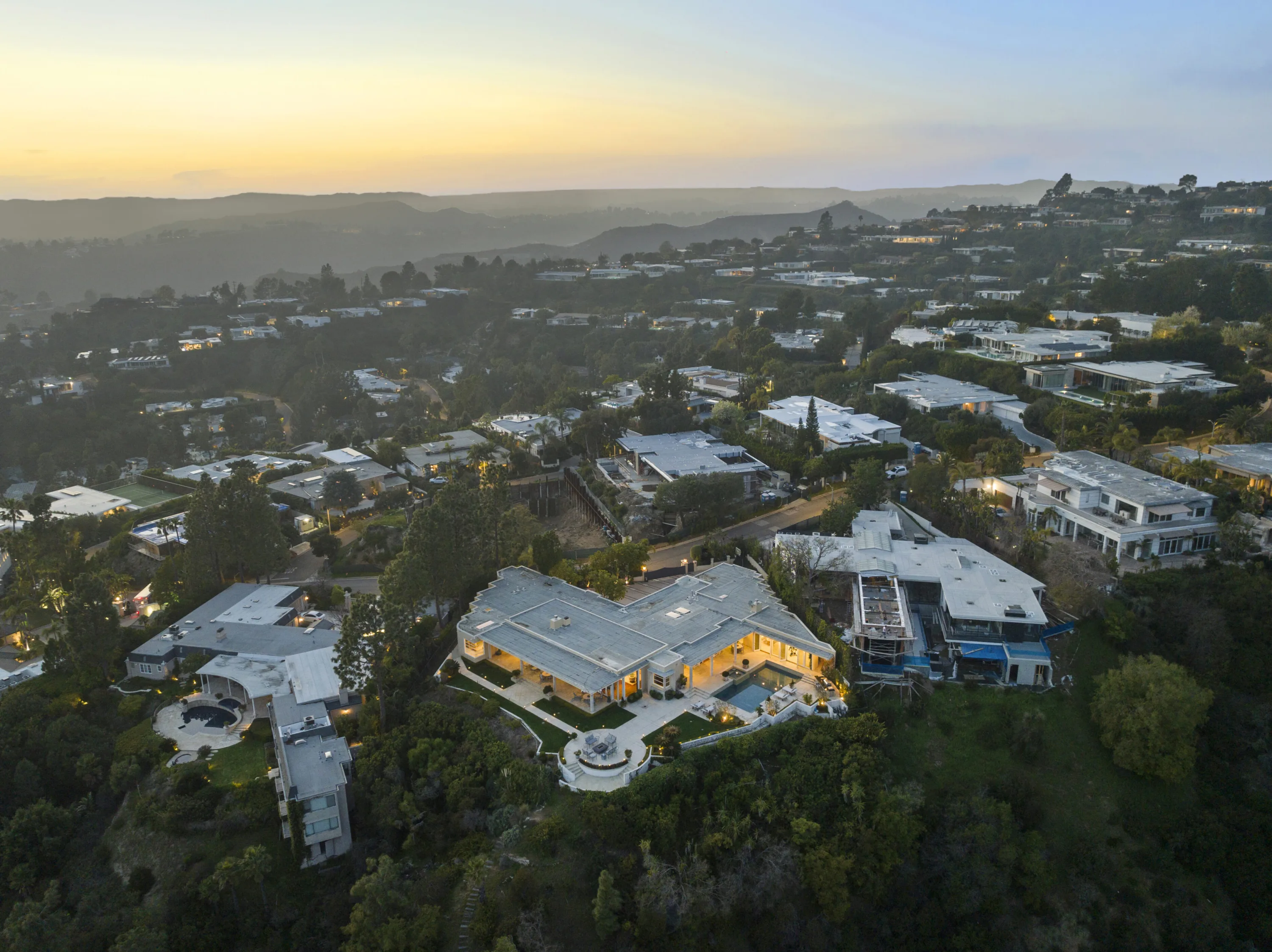 Aerial over Trousdale Estates at sunset, the low-slung house and its pool set on a hilltop ridge