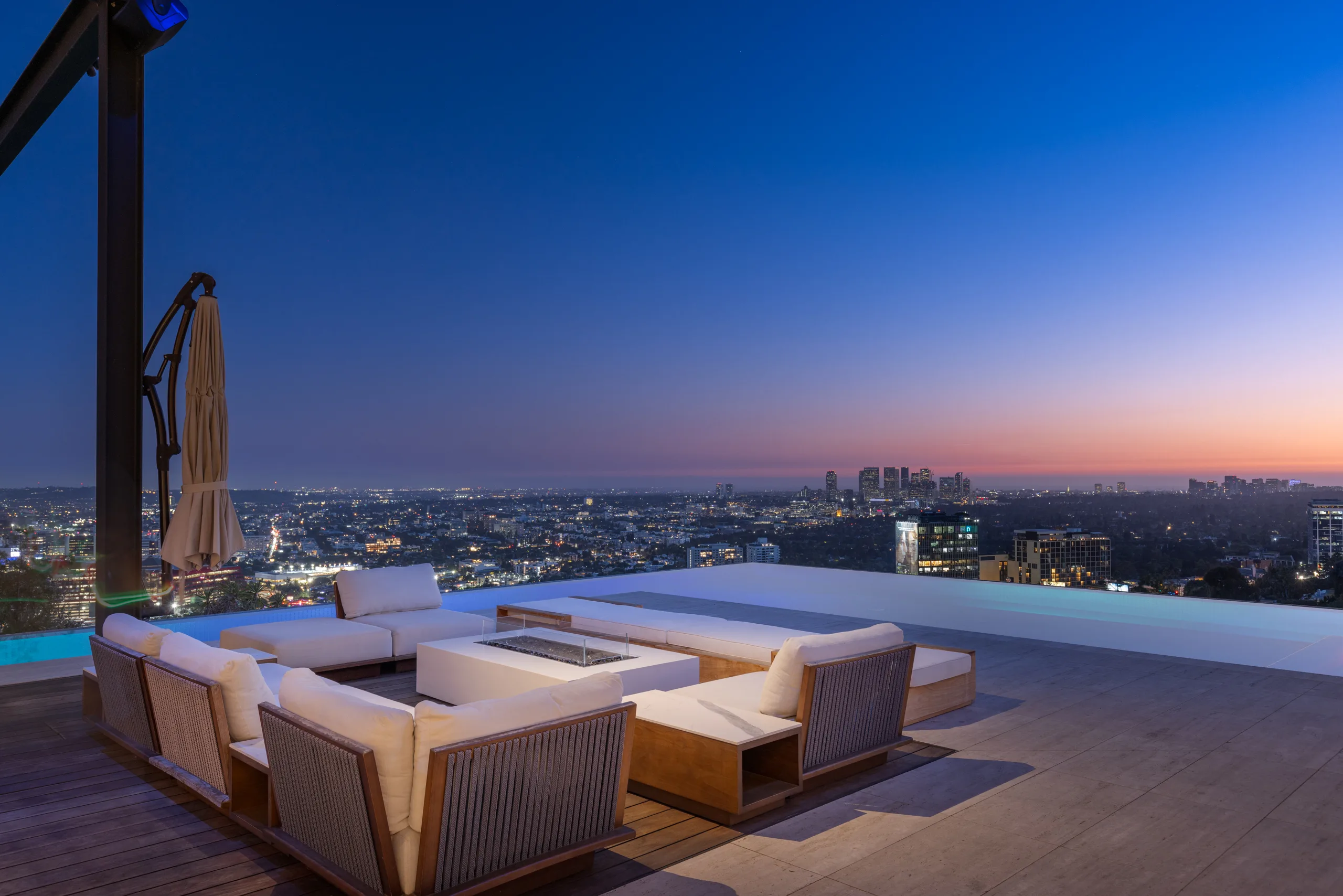 Fire-pit lounge on the pool deck at dusk, city lights stretching to the Century City skyline