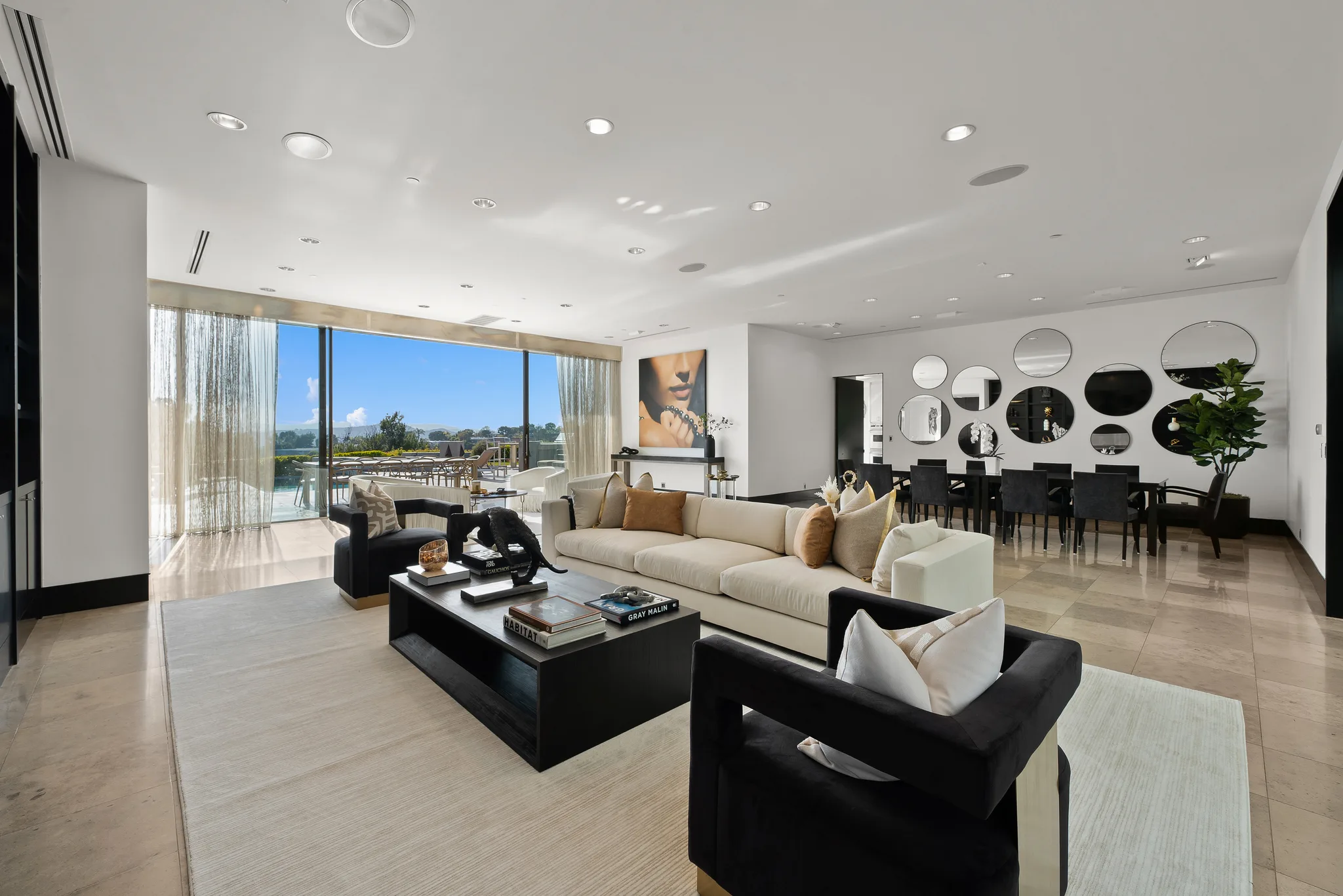 Daytime living and dining area, black velvet armchairs and coffee-table books including "Gray Malin"