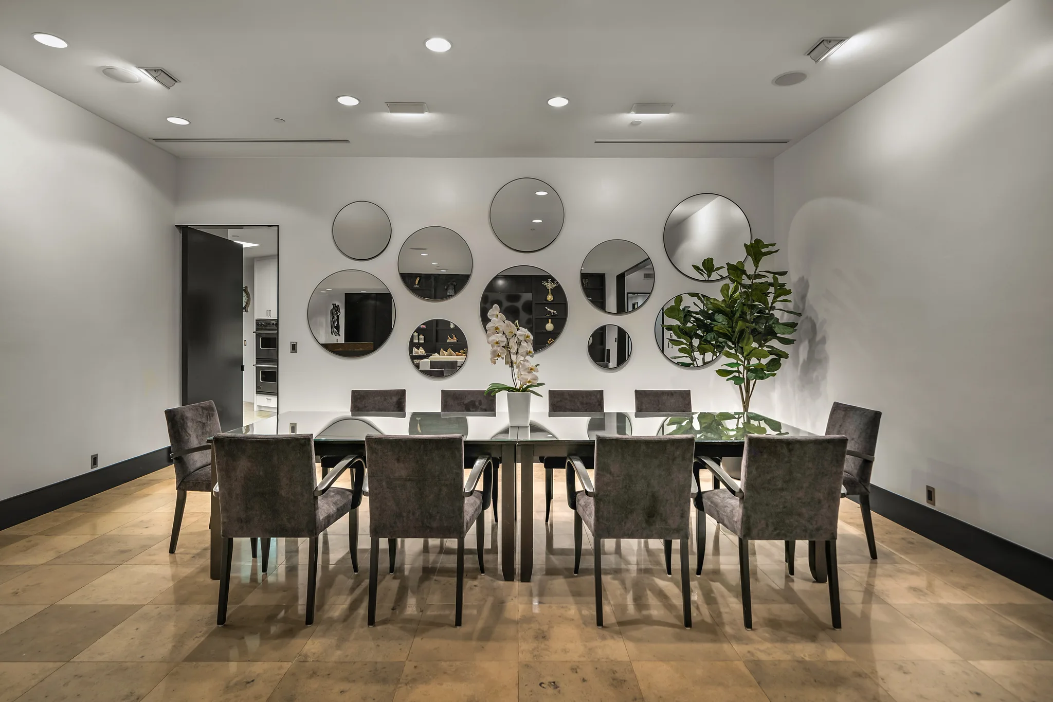 Formal dining room seating ten, glass table beneath a cluster of round mirrors