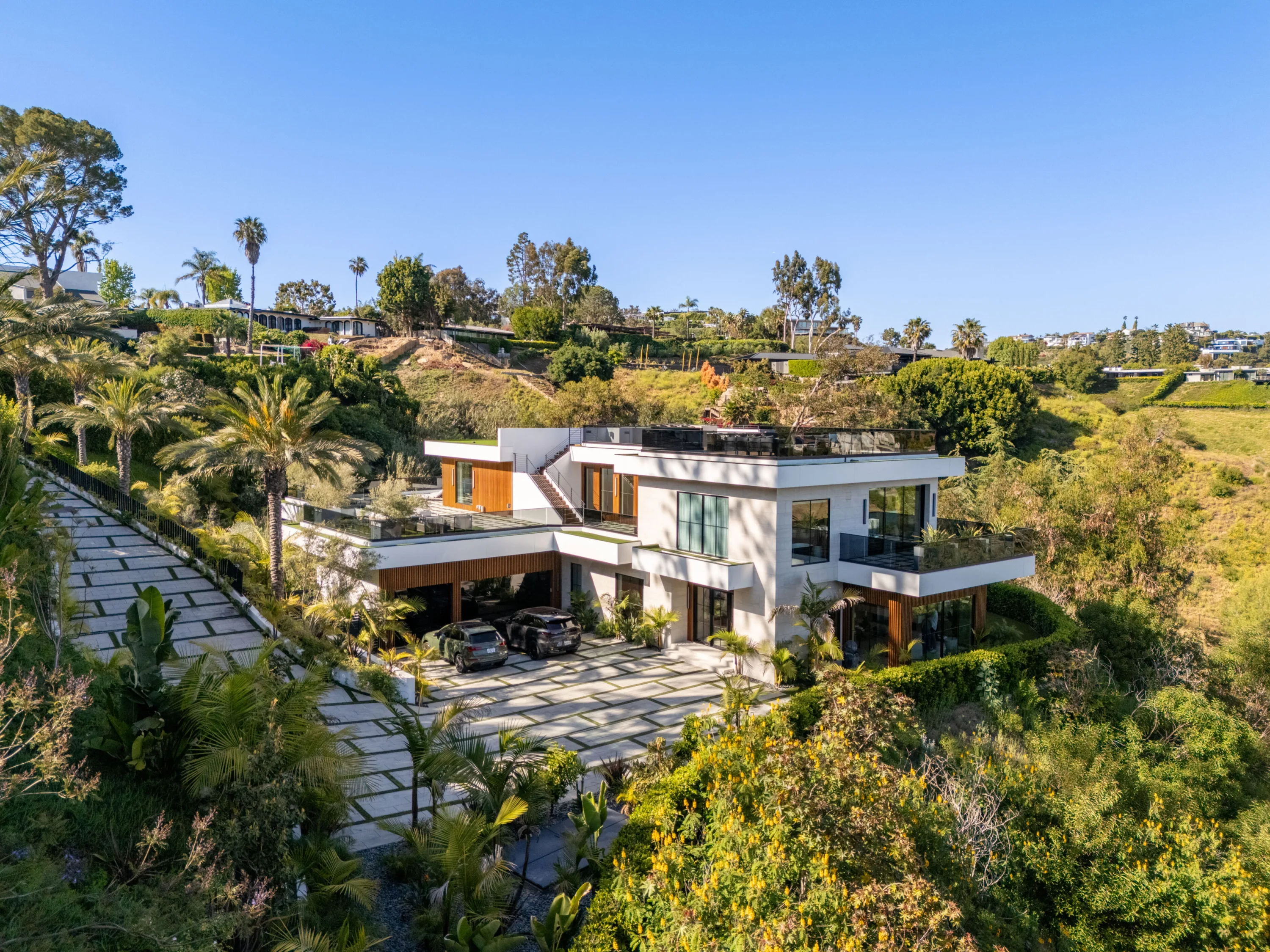 Aerial view of a modern Bel Air villa stepping down a palm-filled hillside above a wide stone motor court