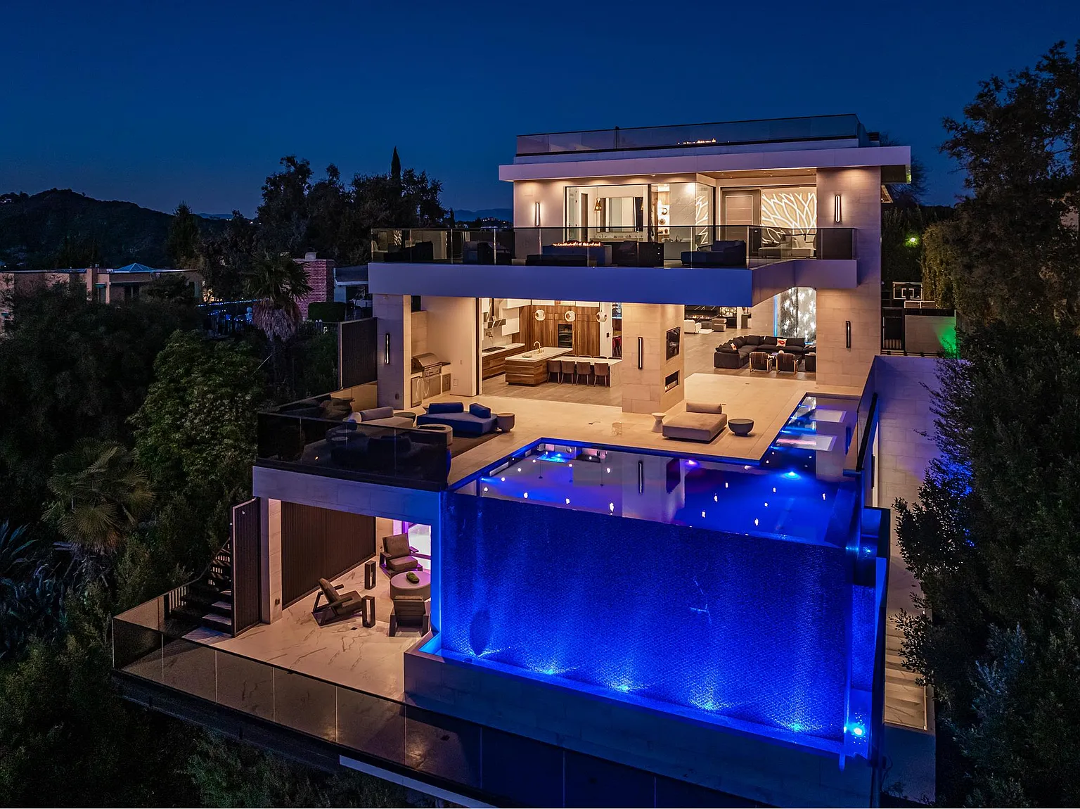 Bel Air Triumph at dusk, its glass-walled infinity pool glowing blue above stacked open-air living terraces