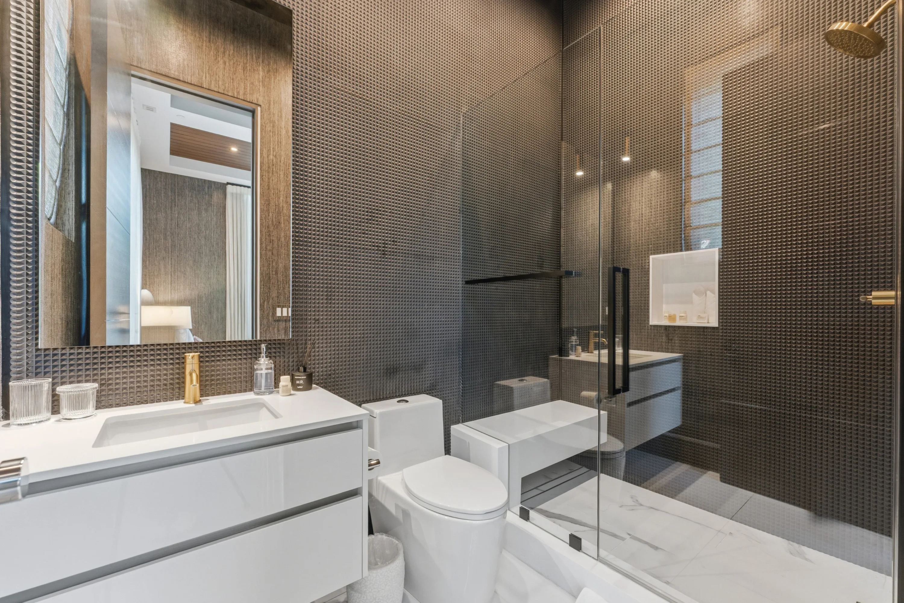 Ensuite in bronze mosaic tile with brushed-gold shower fittings and a crisp white vanity