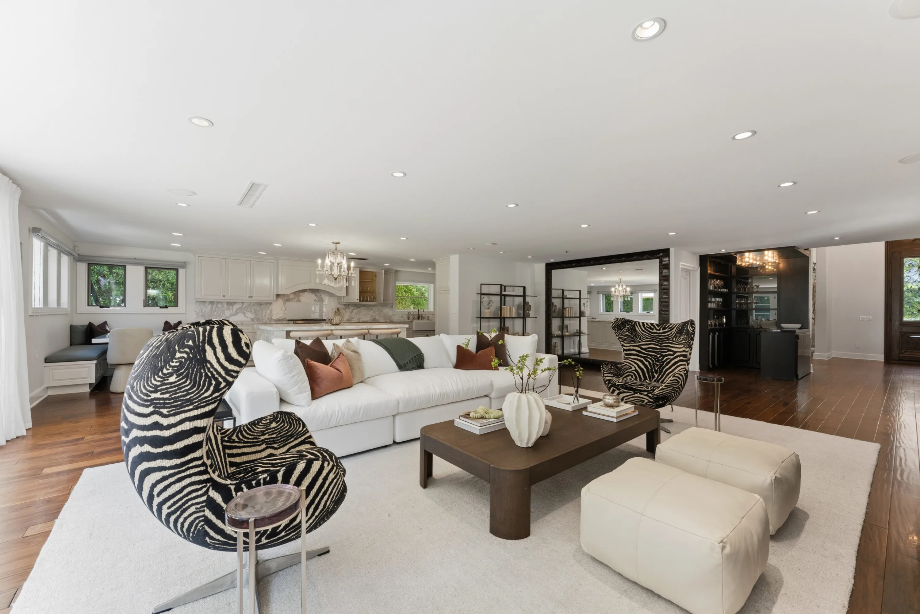 Sprawling den with sectional sofa, leather ottomans and a dark wet bar tucked beyond