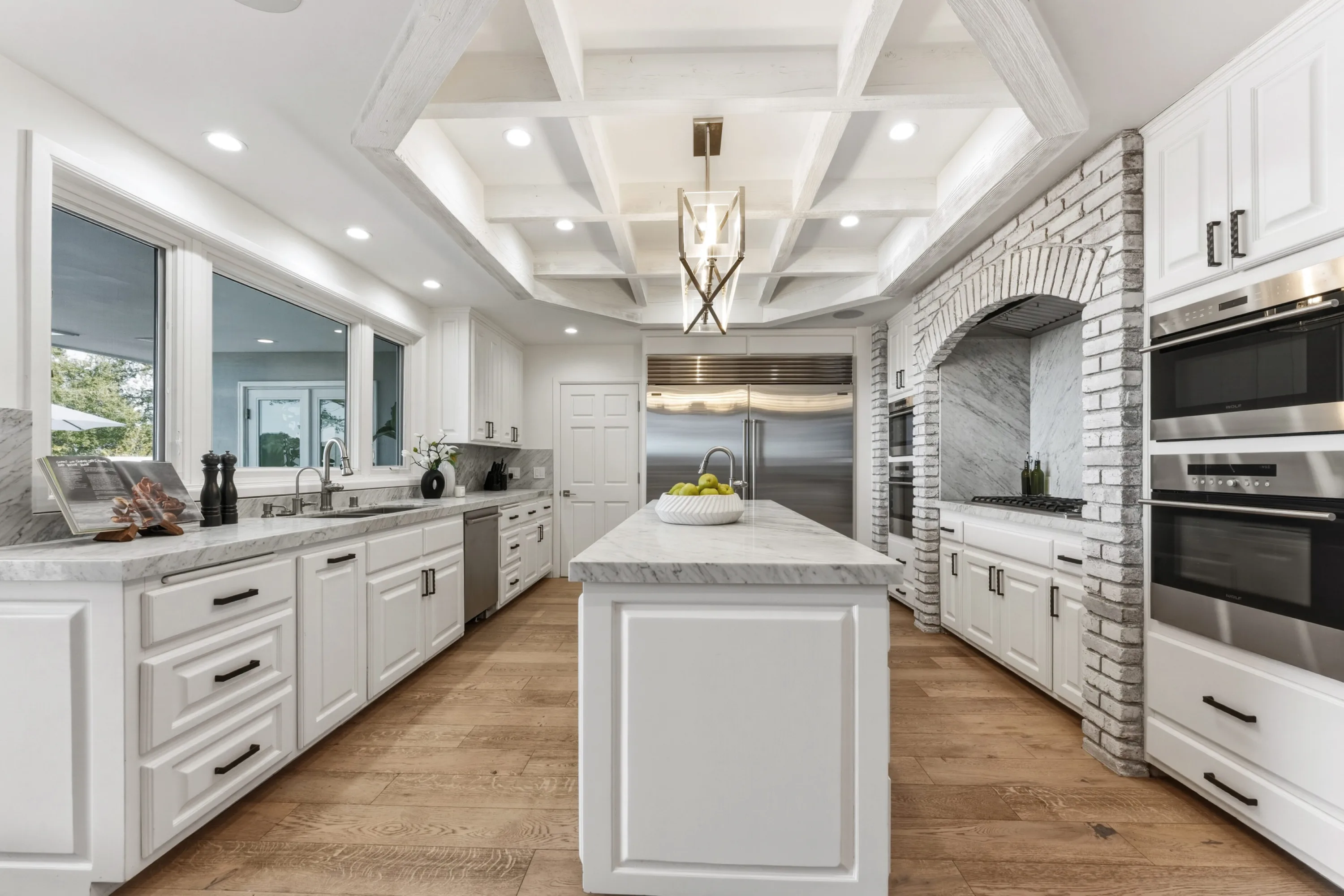 Chef's kitchen with marble counters, coffered ceiling, double ovens and a brick-arched range alcove