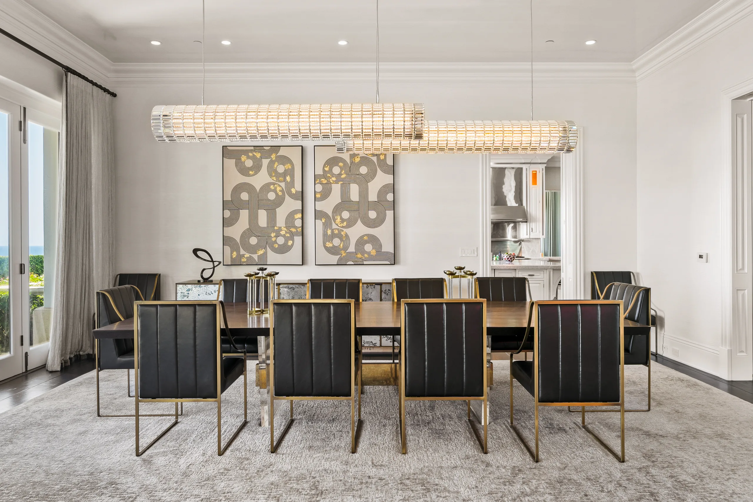 Formal dining room seating ten in black leather and brass beneath twin crystal bar chandeliers