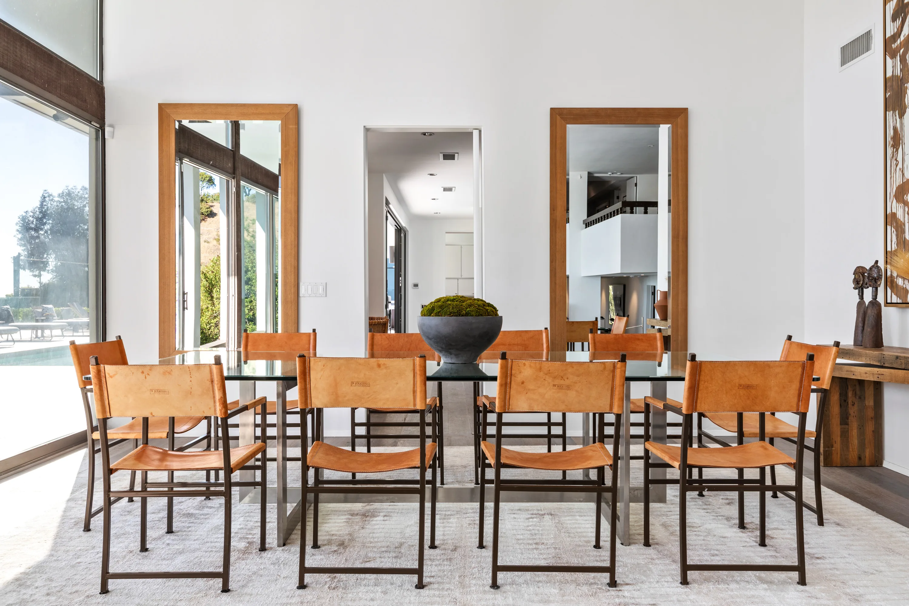 Formal dining room seating ten, glass table and leather sling chairs beside sliders to the pool