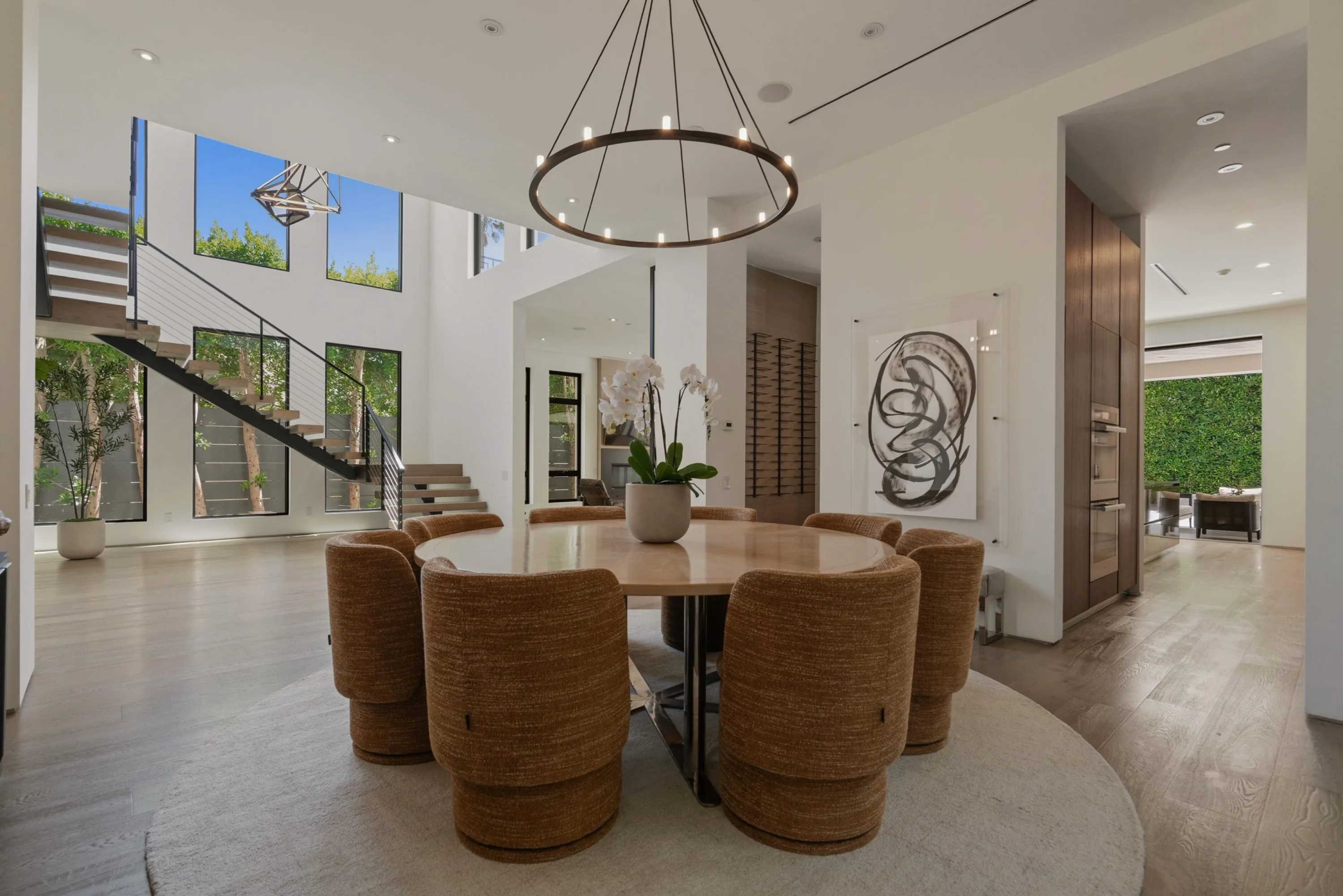 Round dining table set below the two-storey atrium and open-tread staircase