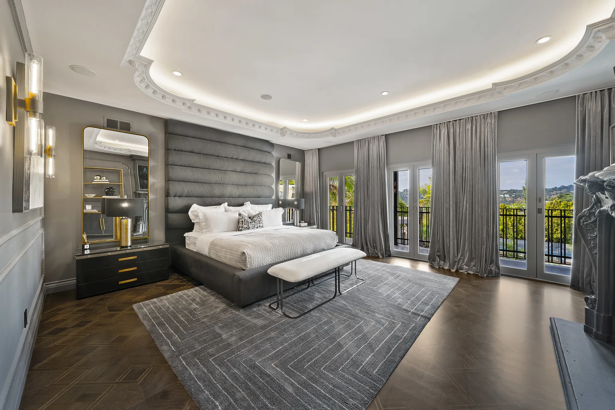Primary suite in grey velvet with channelled headboard and French doors onto a view balcony