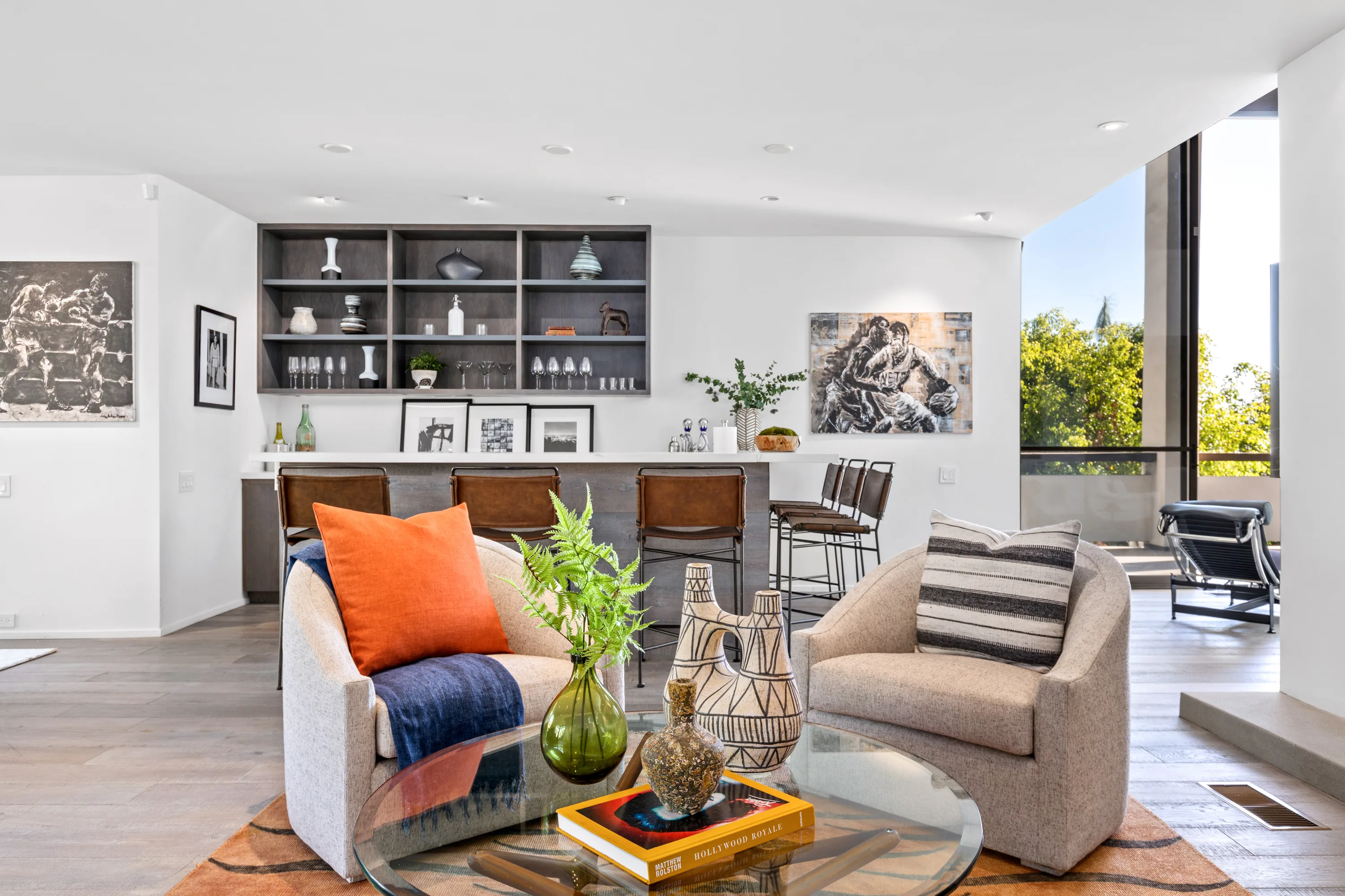 Den and wet bar with leather stools, swivel chairs and sliding glass to a shaded terrace