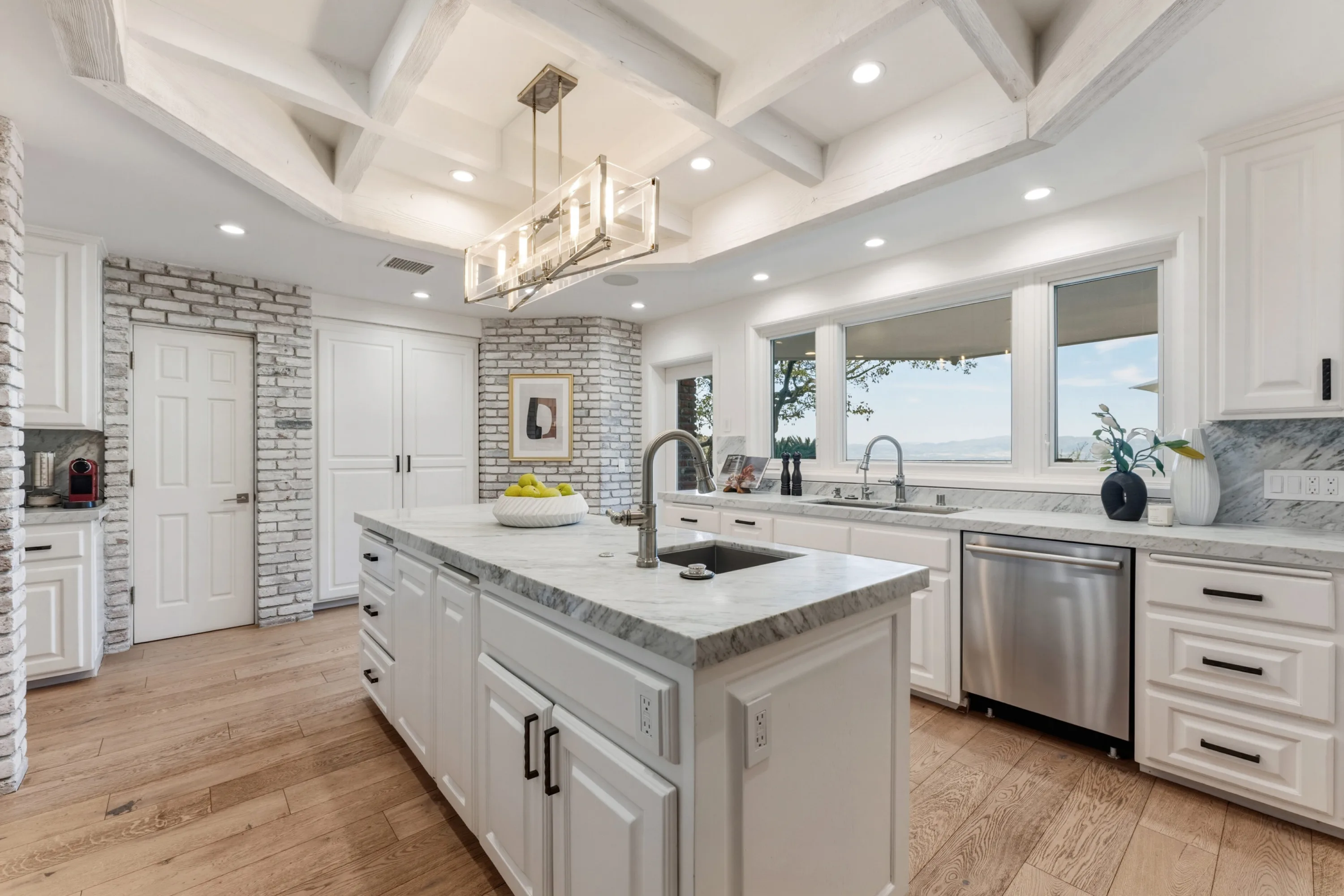Prep island with marble waterfall counter and picture windows framing treetops and distant hills