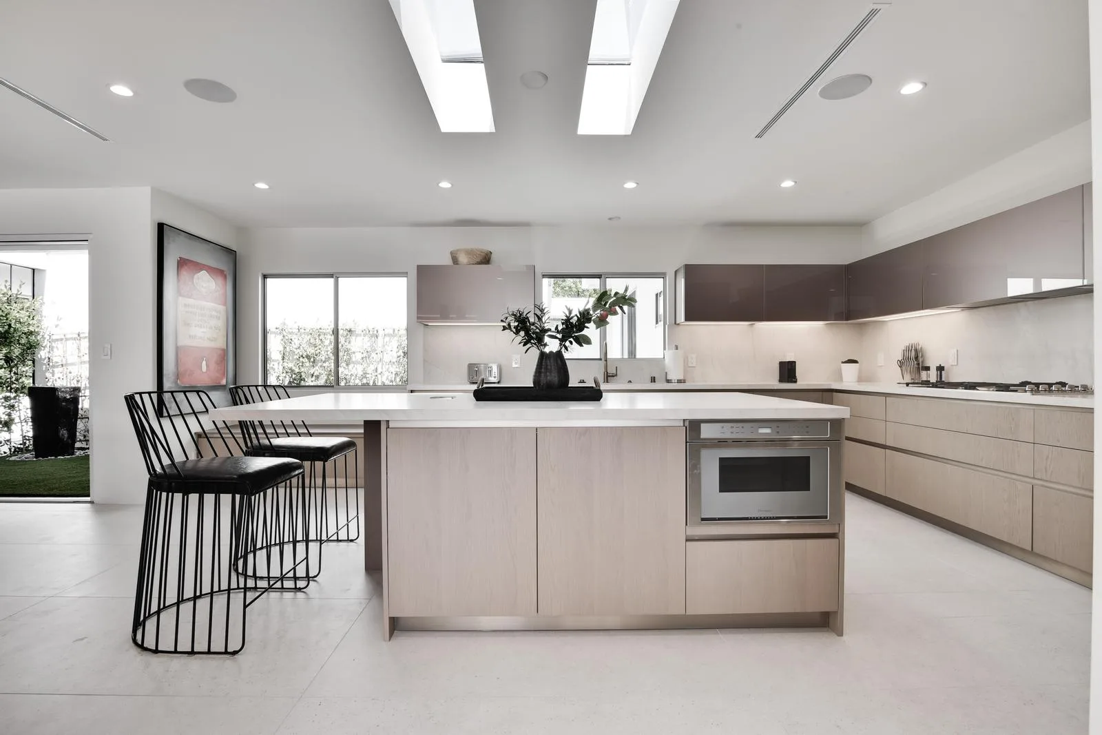 Kitchen island with black wire counter stools, built-in oven and gas range along the rear run