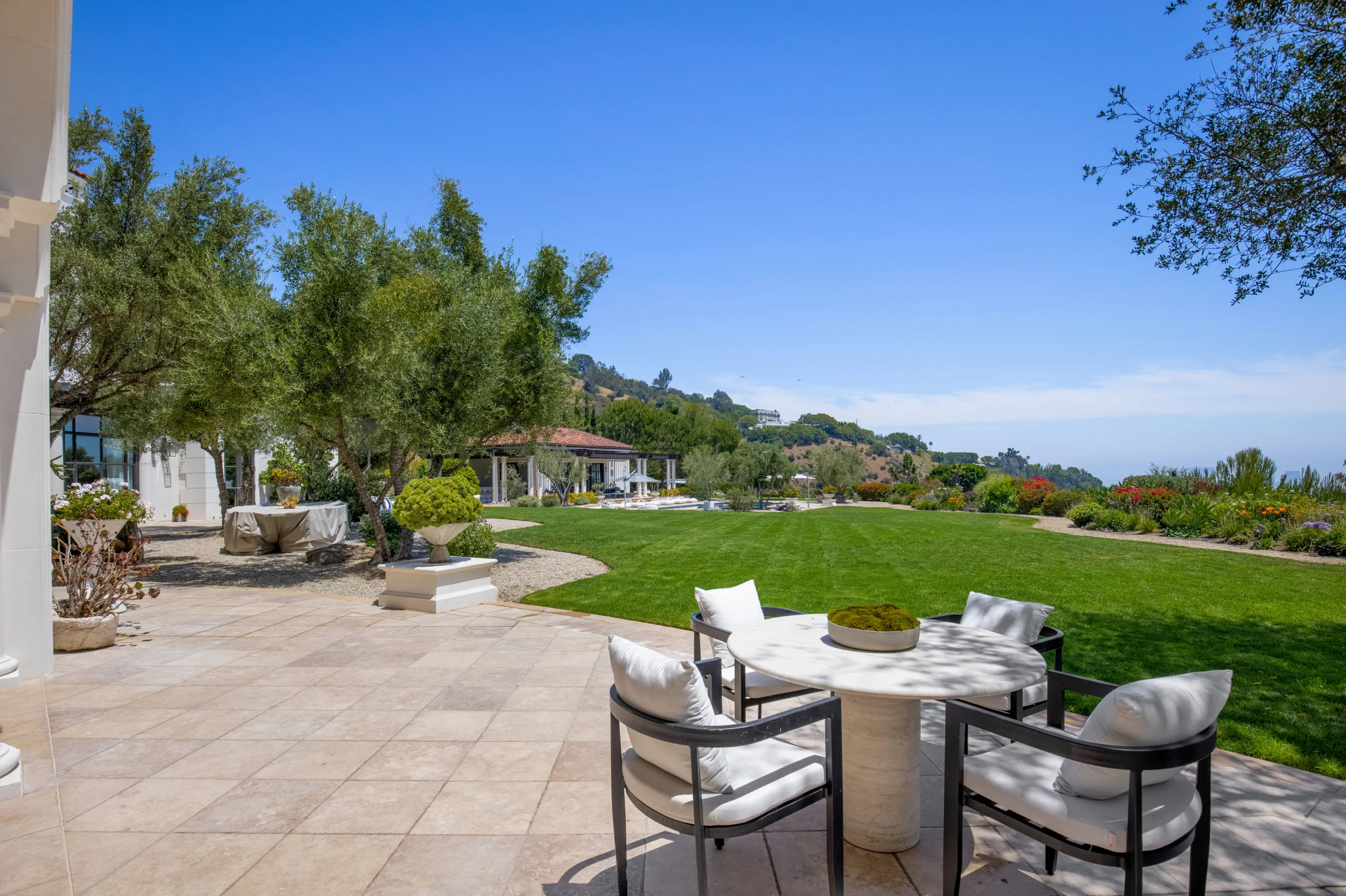 Travertine terrace dining set overlooking the great lawn, olive grove and distant pool house