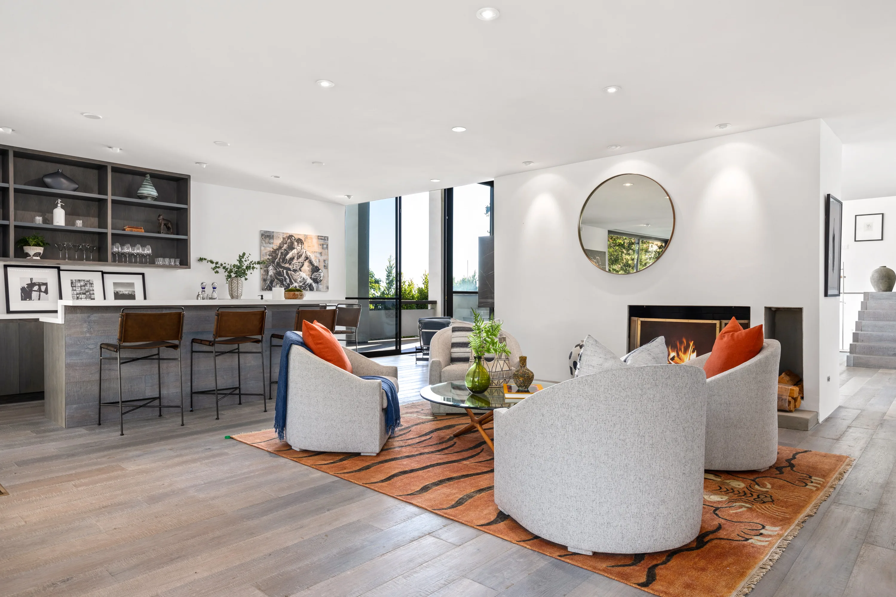 Family lounge with bar counter, tiger-print rug and lit fireplace under a round mirror