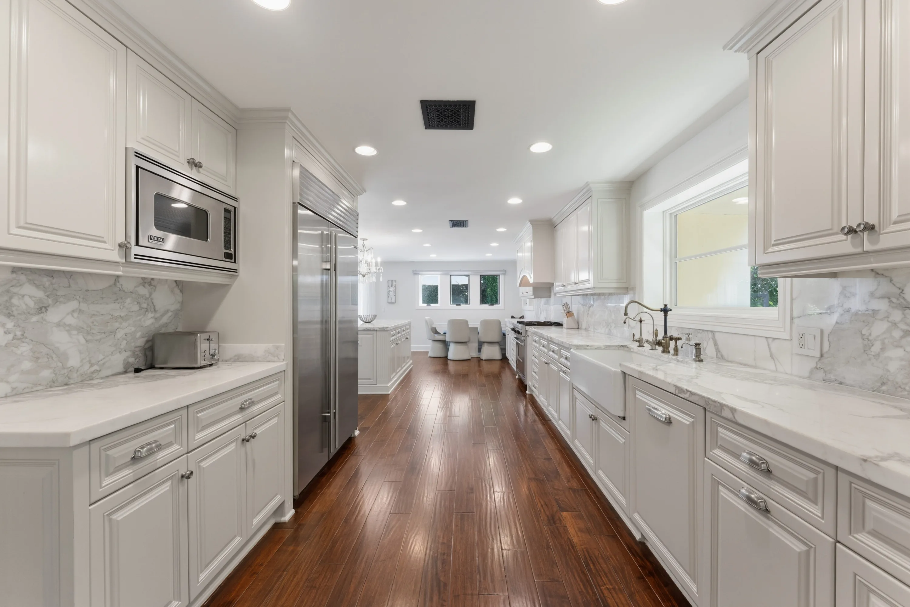 Galley prep kitchen with marble counters, farmhouse sink and built-in stainless fridge