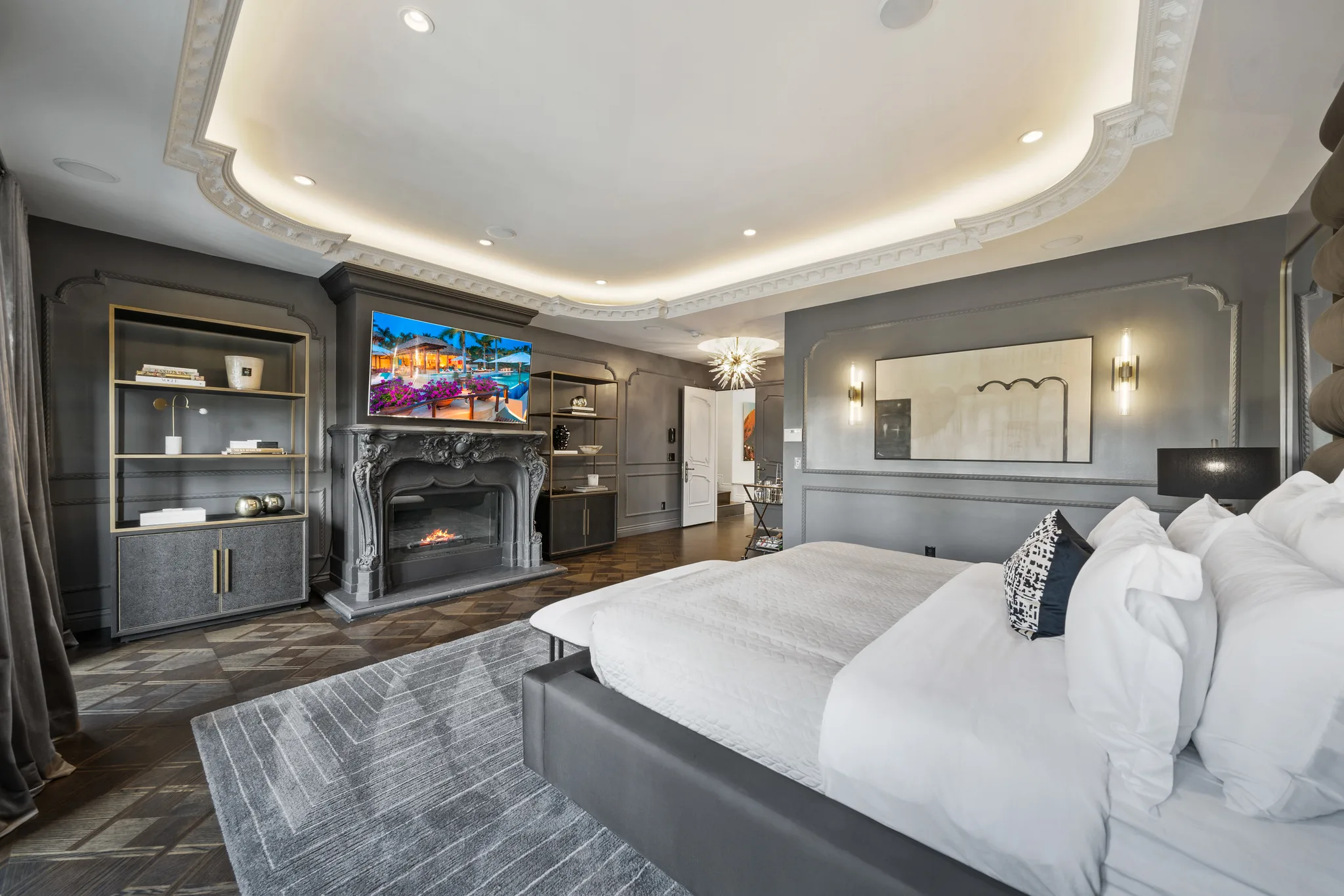 King bed facing a carved stone fireplace and built-in shelving in the main suite