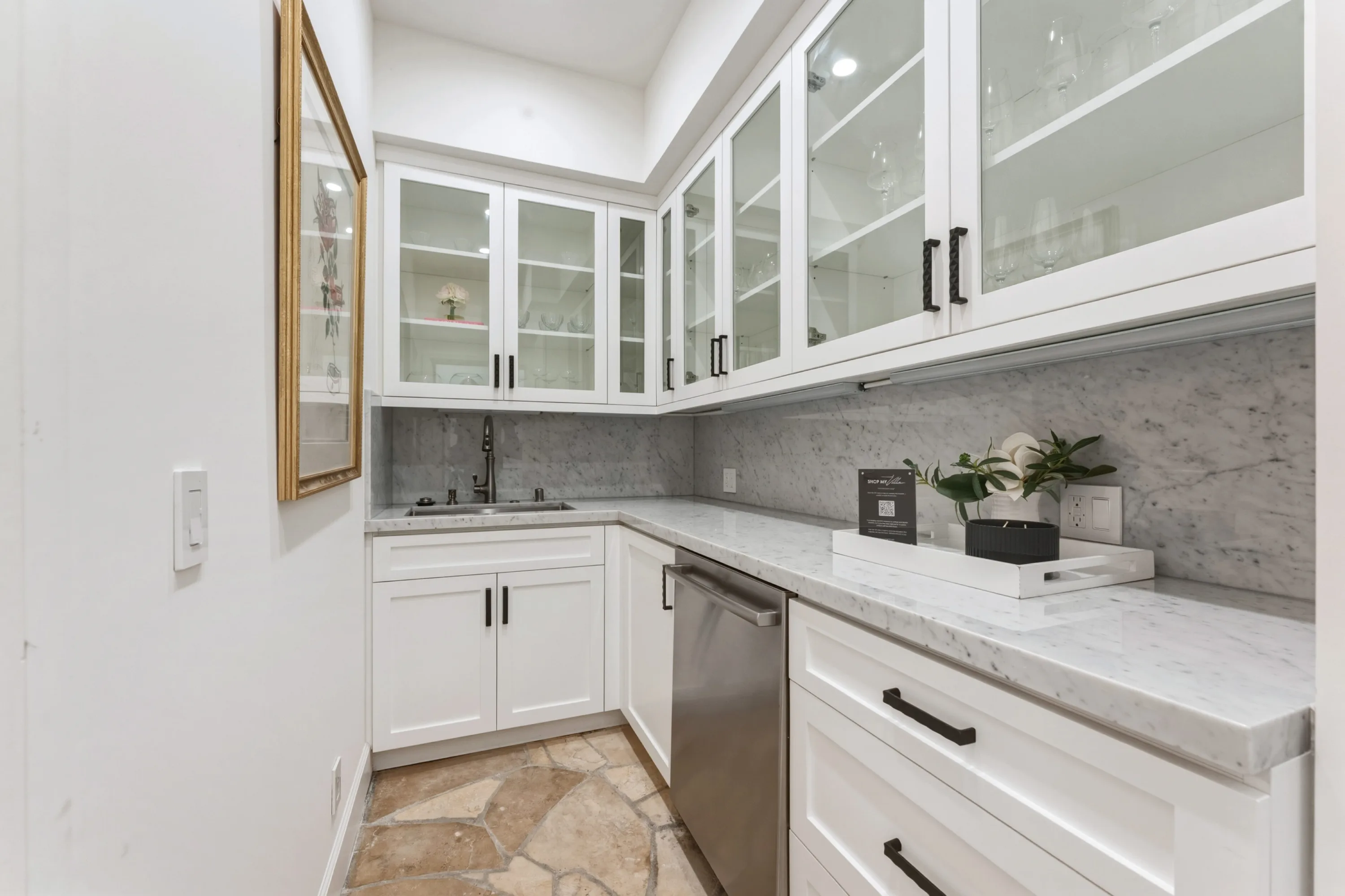 Butler's pantry with glass-front cabinets, marble backsplash, prep sink and stone-tiled floor