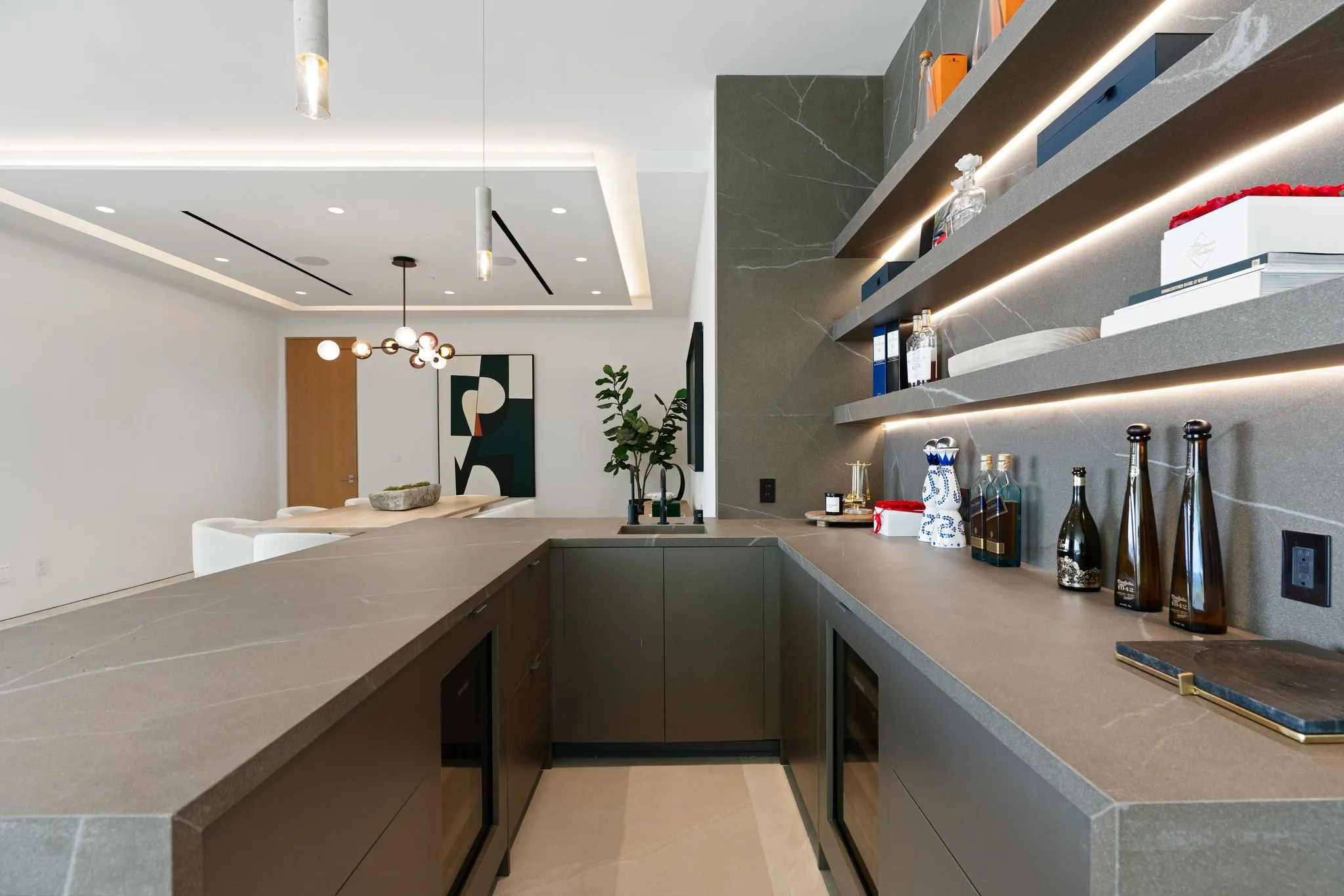 Close view of the bar counter, wine fridge and illuminated stone shelves stocked with bottles