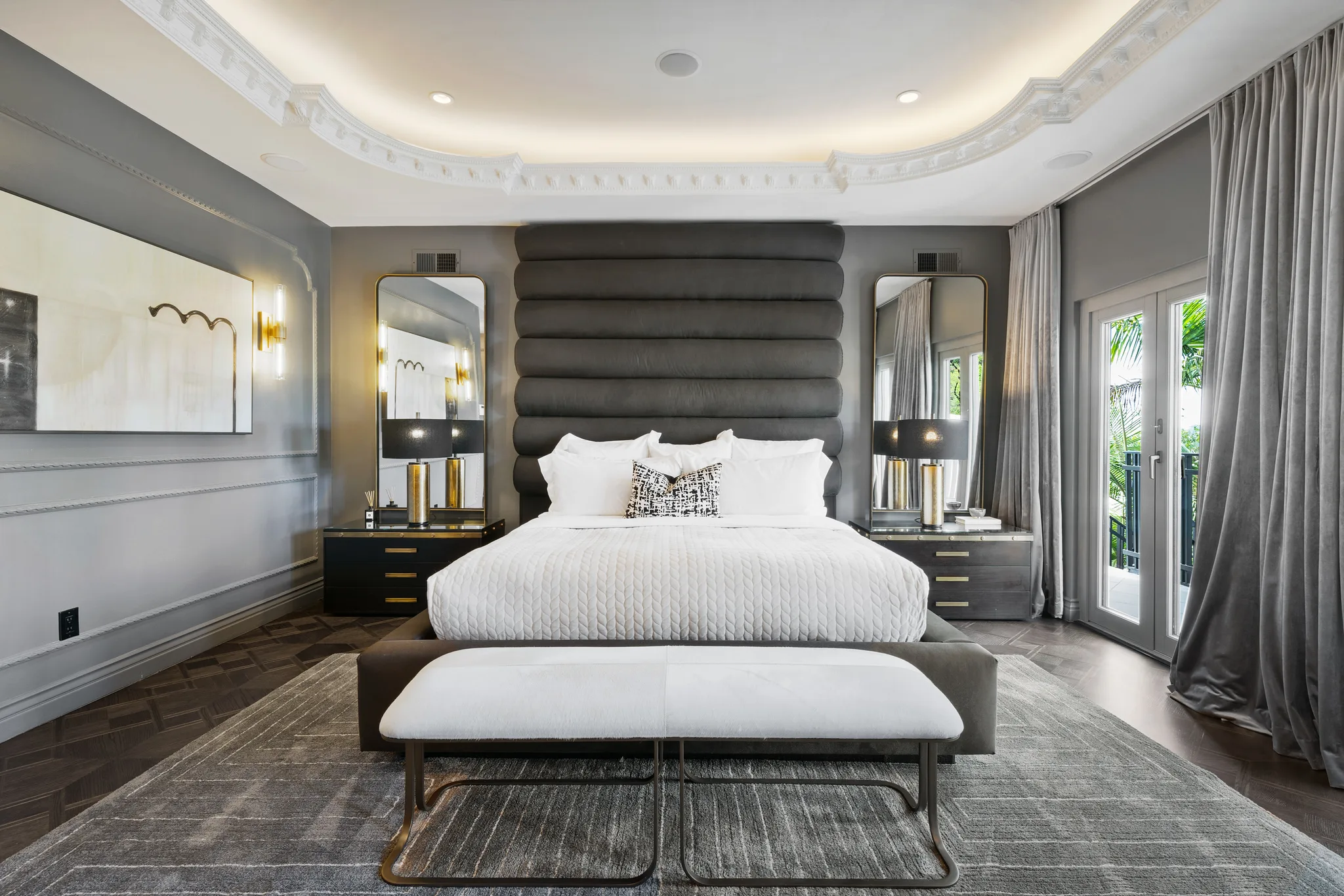 Symmetrical bedroom setting with tall padded headboard, twin mirrors and upholstered end bench