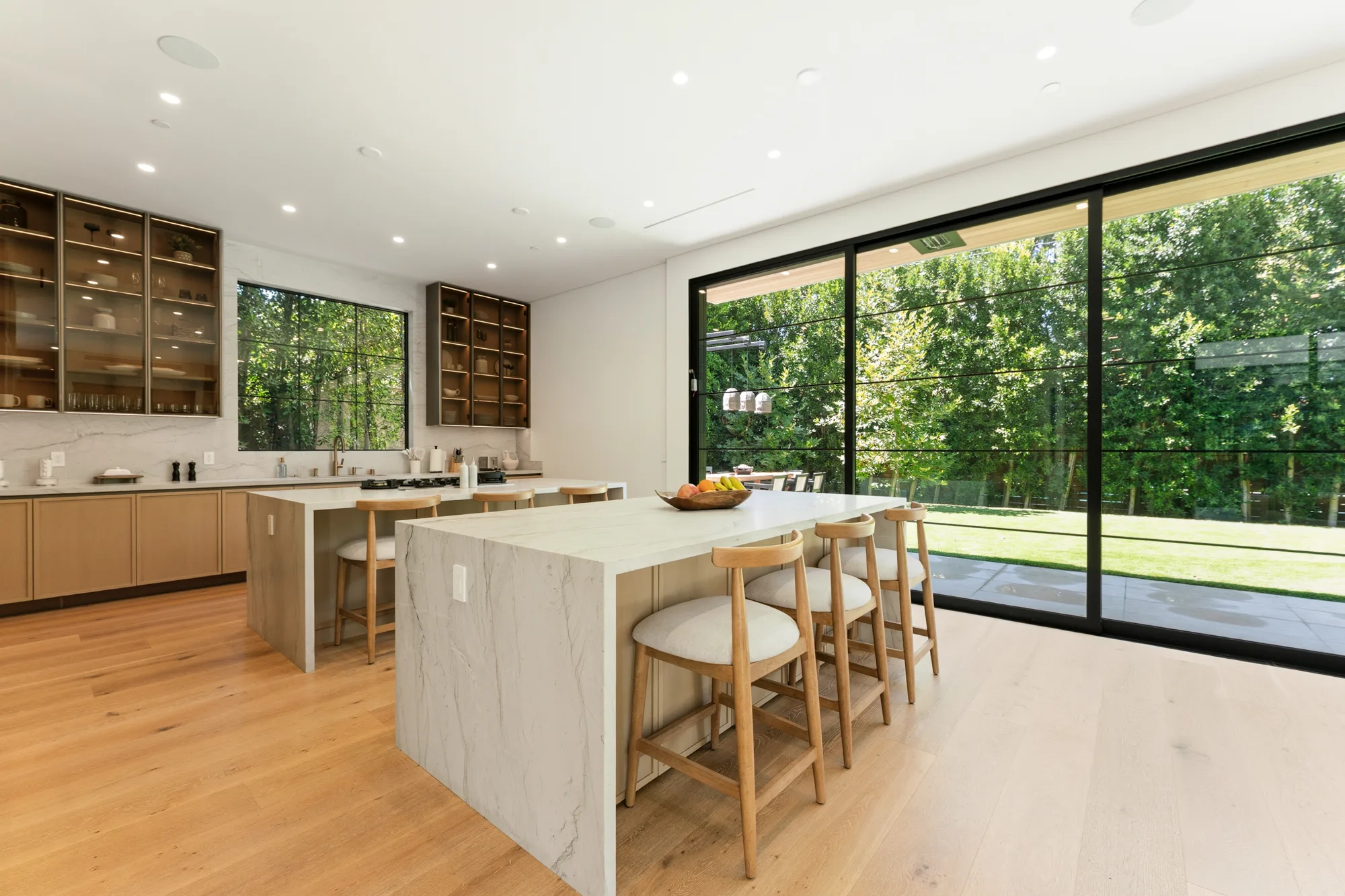 Second kitchen island and stools beside sliding glass opening to the lawn and pool terrace
