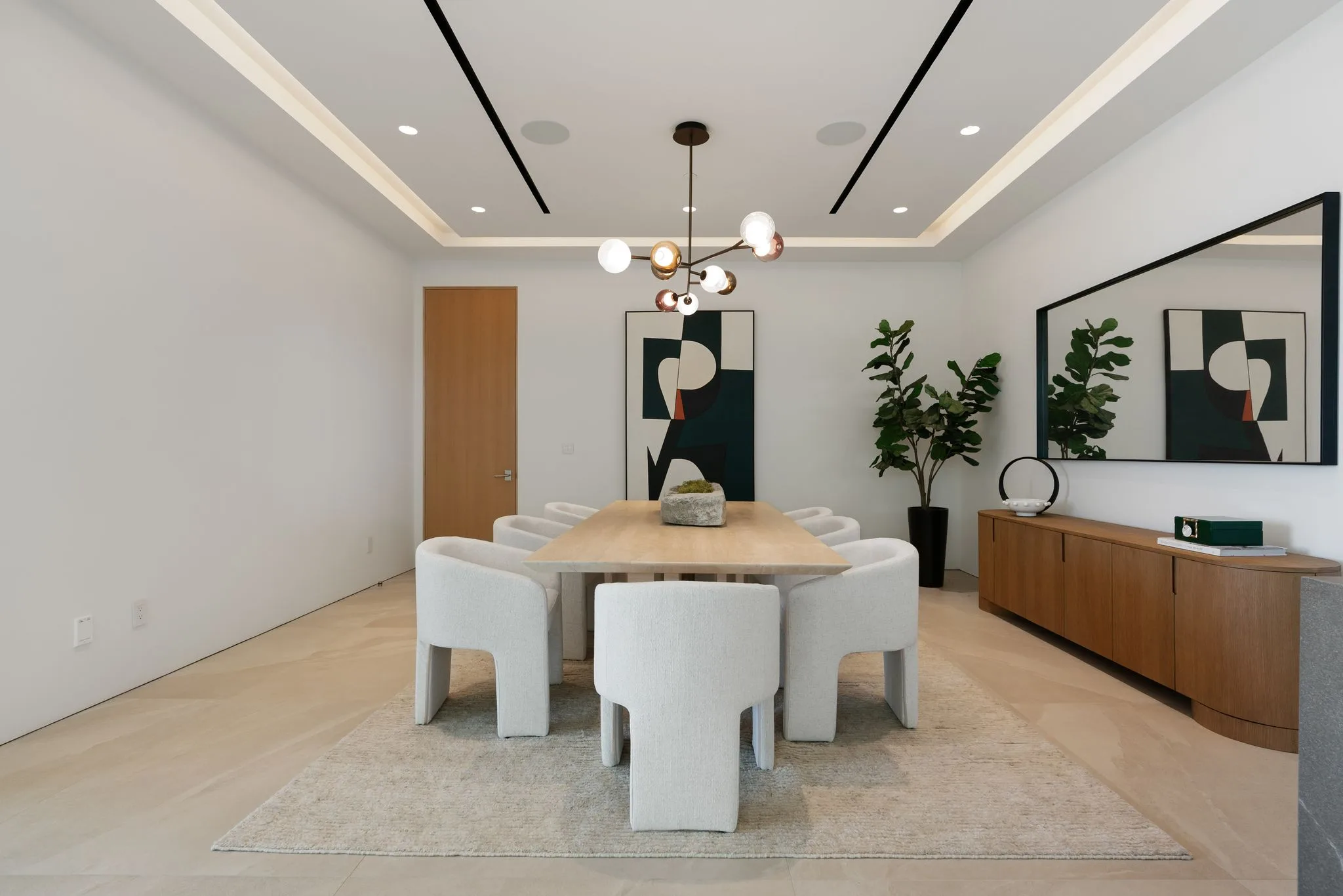 Formal dining room seating eight under a brass globe chandelier, with graphic artwork and credenza