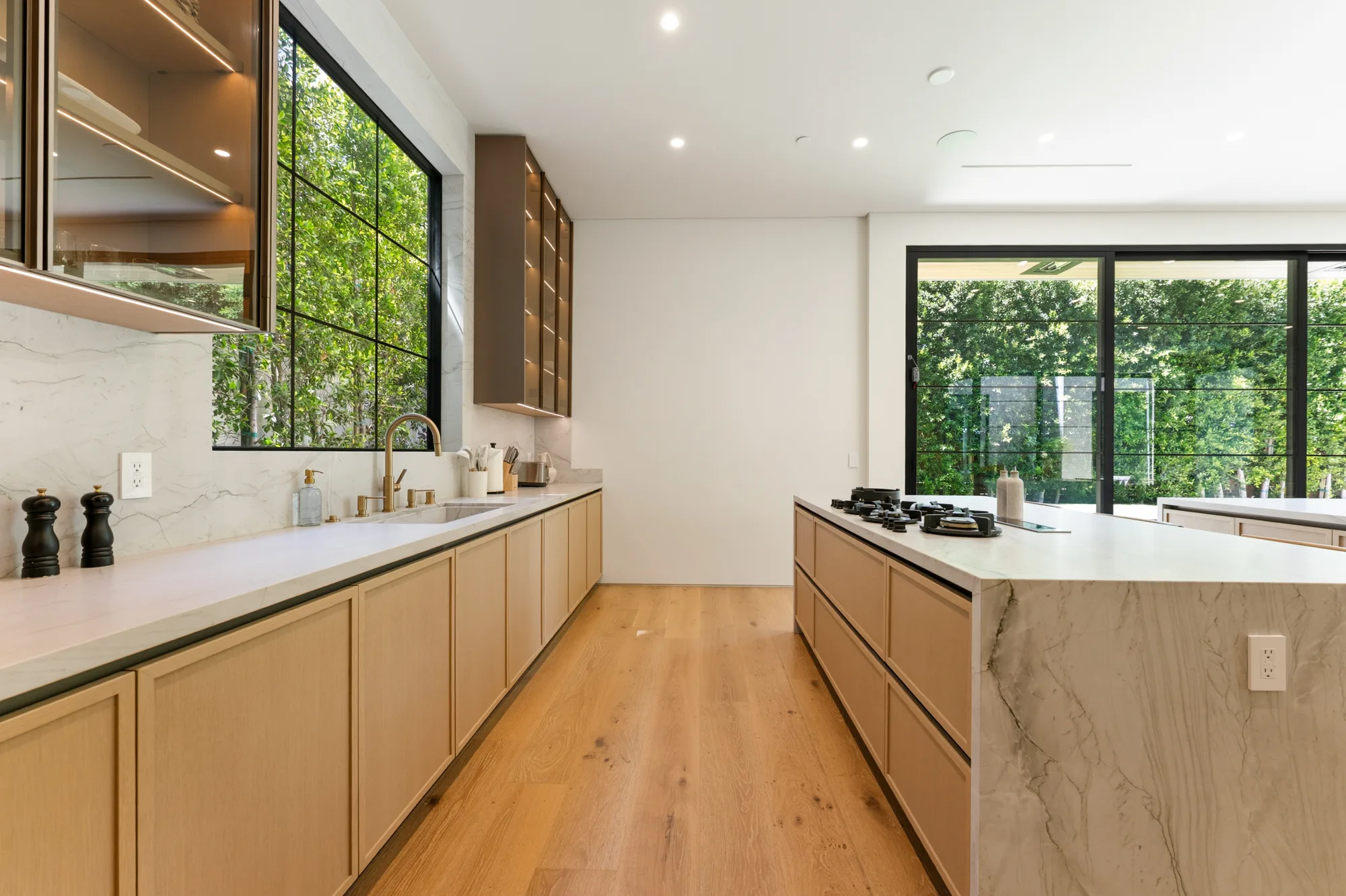 Kitchen prep run with marble counters, brass tap and gas cooktop on the adjoining island