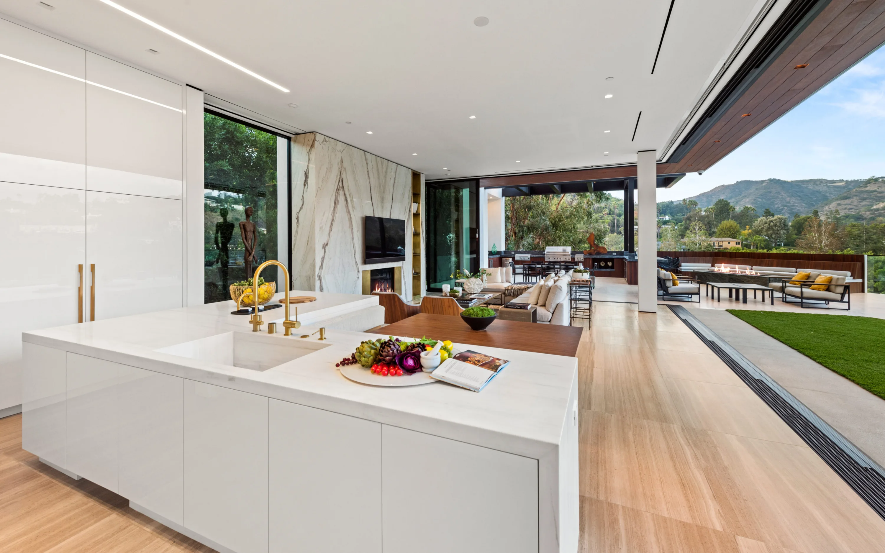 Kitchen island with brass tap looking through the family room to the grill terrace and mountains