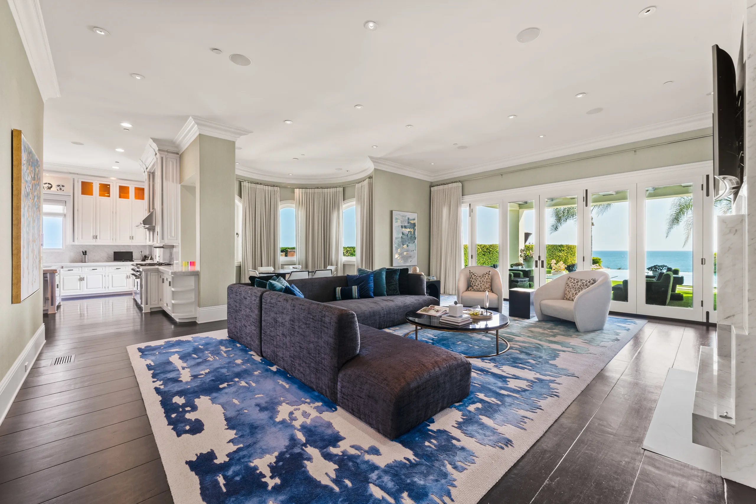 Family room off the kitchen, charcoal sectional on a blue watercolour rug, French doors to the sea