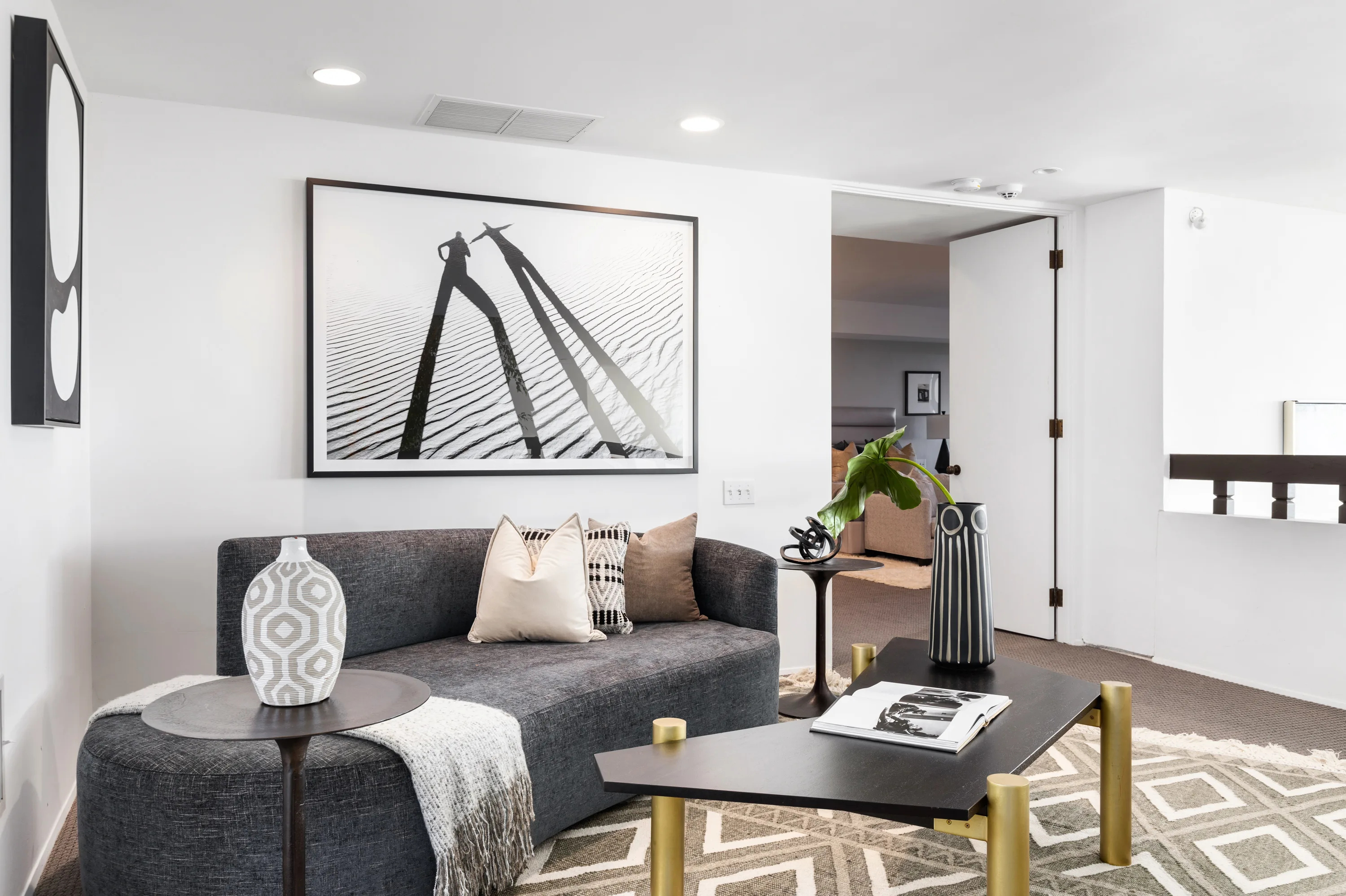 Upstairs sitting nook with charcoal sofa, black-and-white photograph and door through to a bedroom