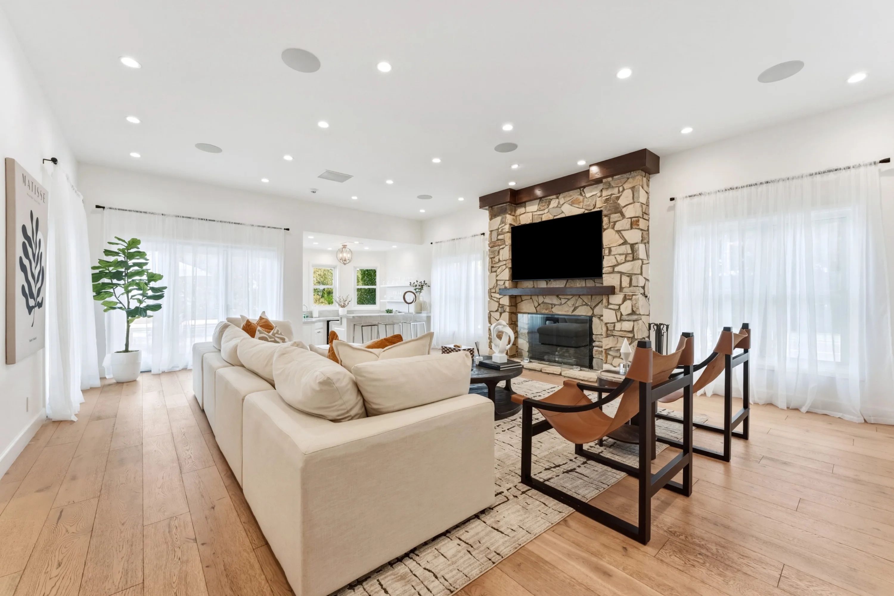 Great room anchored by a floor-to-ceiling stone fireplace, opening through to the breakfast kitchen