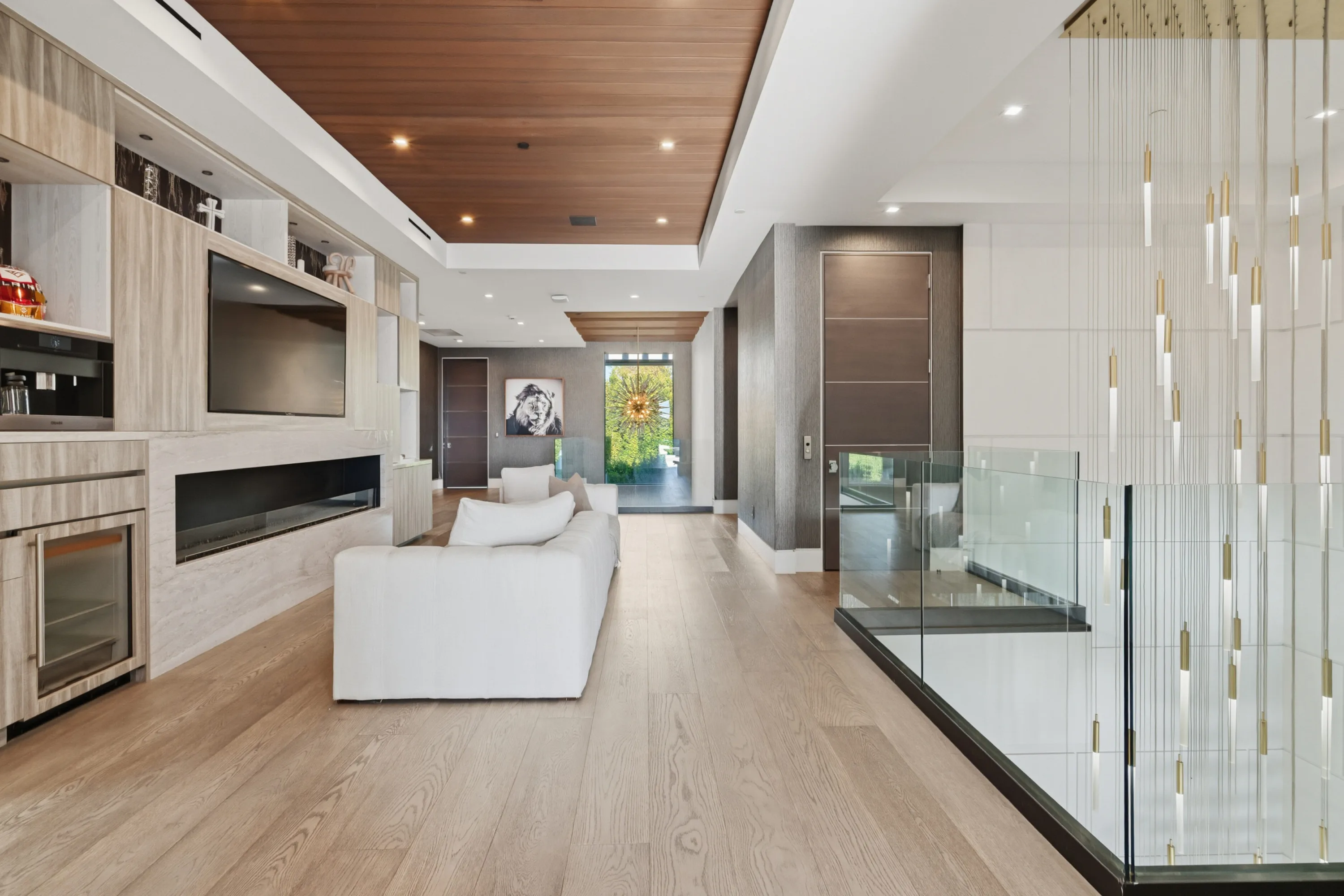 Upper landing lounge with fireplace, wine fridge and TV, looking down the hall to the front door