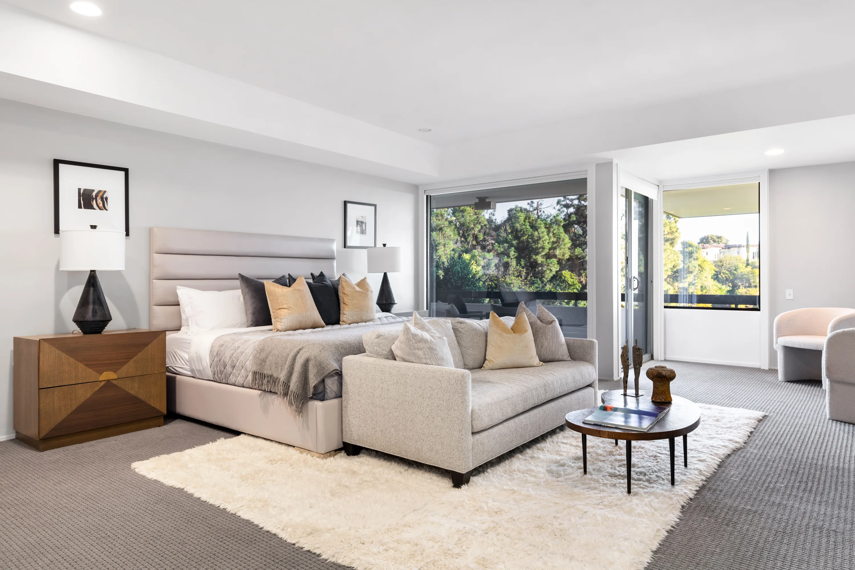 Primary suite with upholstered king bed, sofa at the foot and sliders to a private terrace
