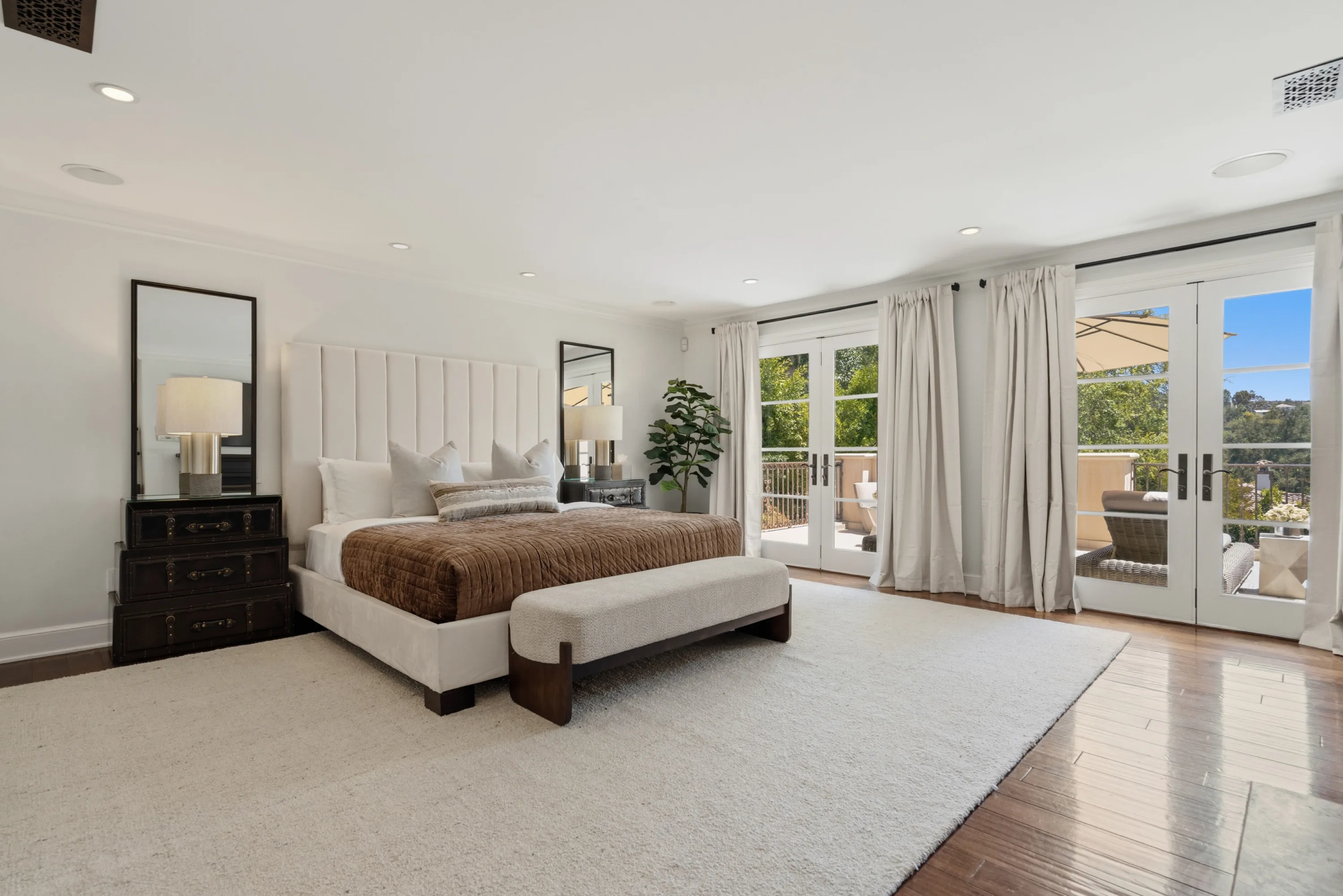 Primary suite with upholstered king bed, velvet throw and French doors opening to a private terrace