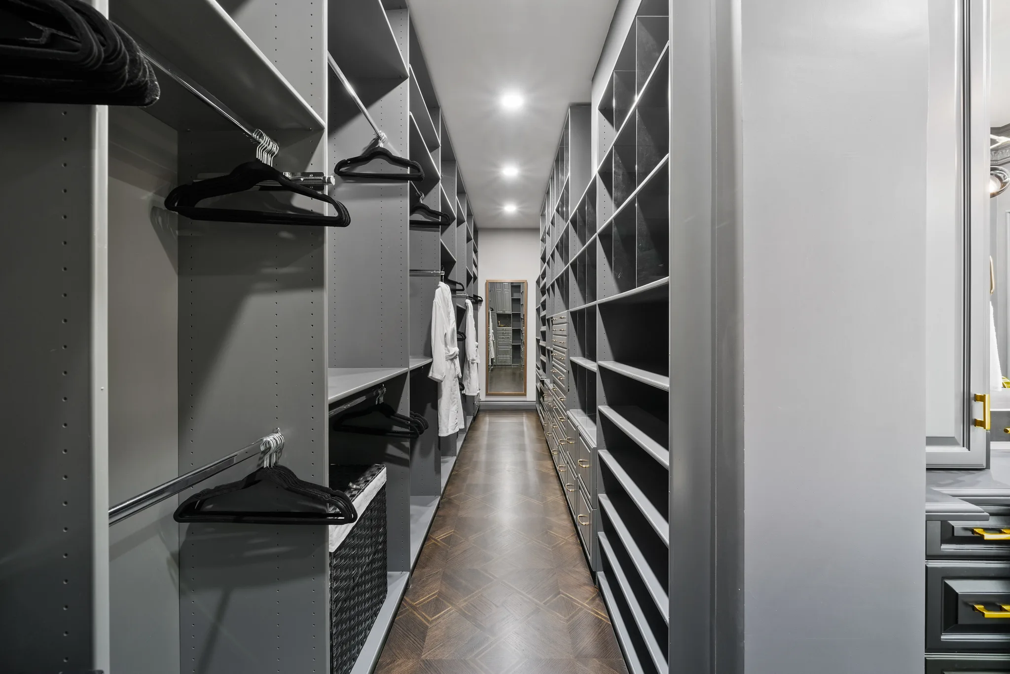 Walk-in dressing room lined with grey shelving, hanging rails and a full-length mirror