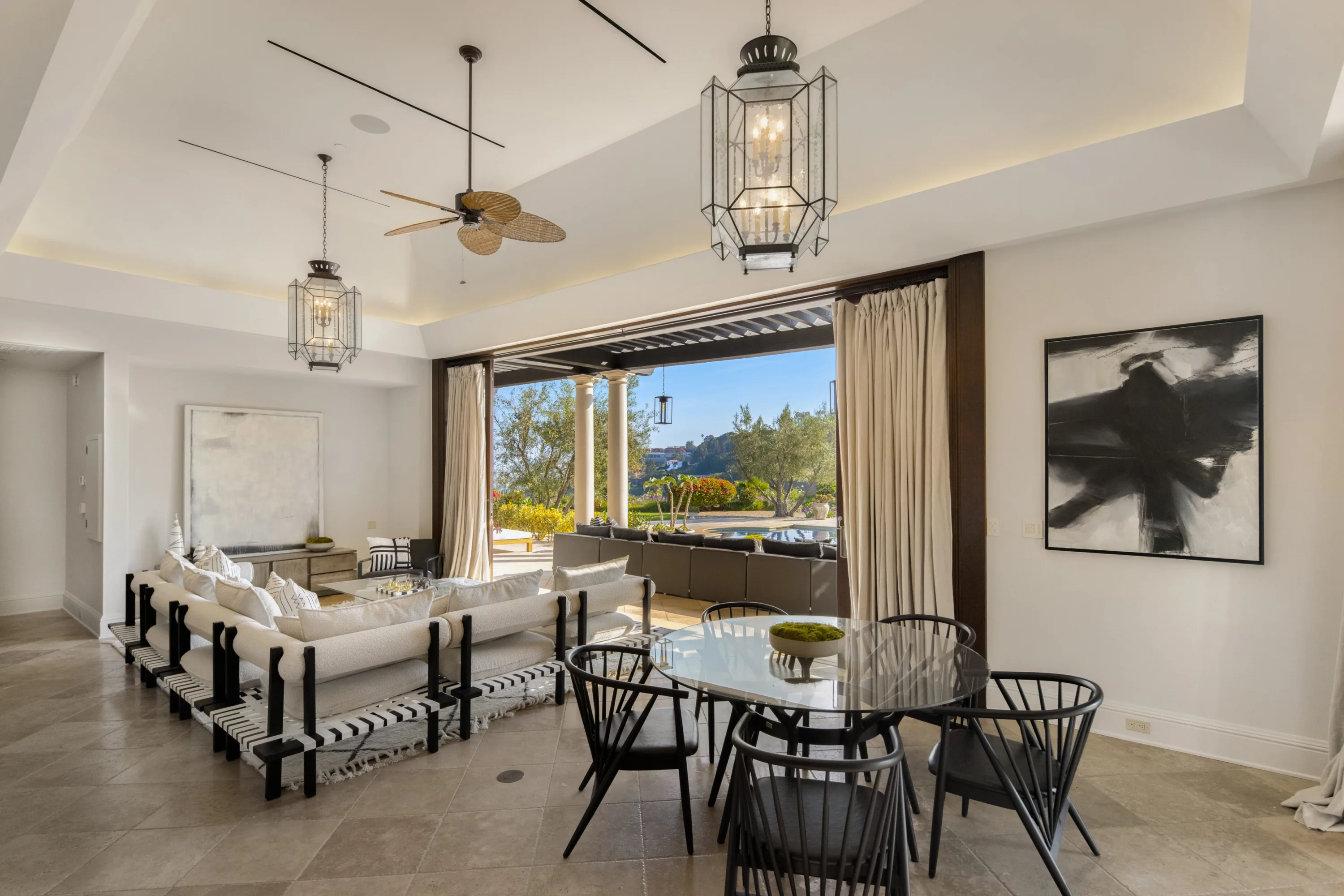 Pool house sitting and games room, lanterns overhead and doors folded open to the terrace