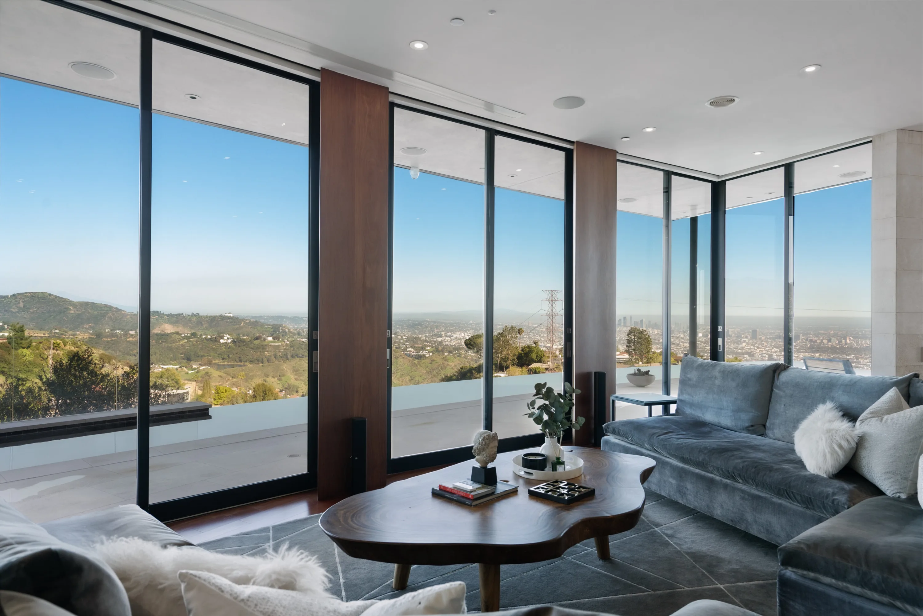 Velvet sectional in the upper lounge, walls of glass opening to the terrace and downtown skyline