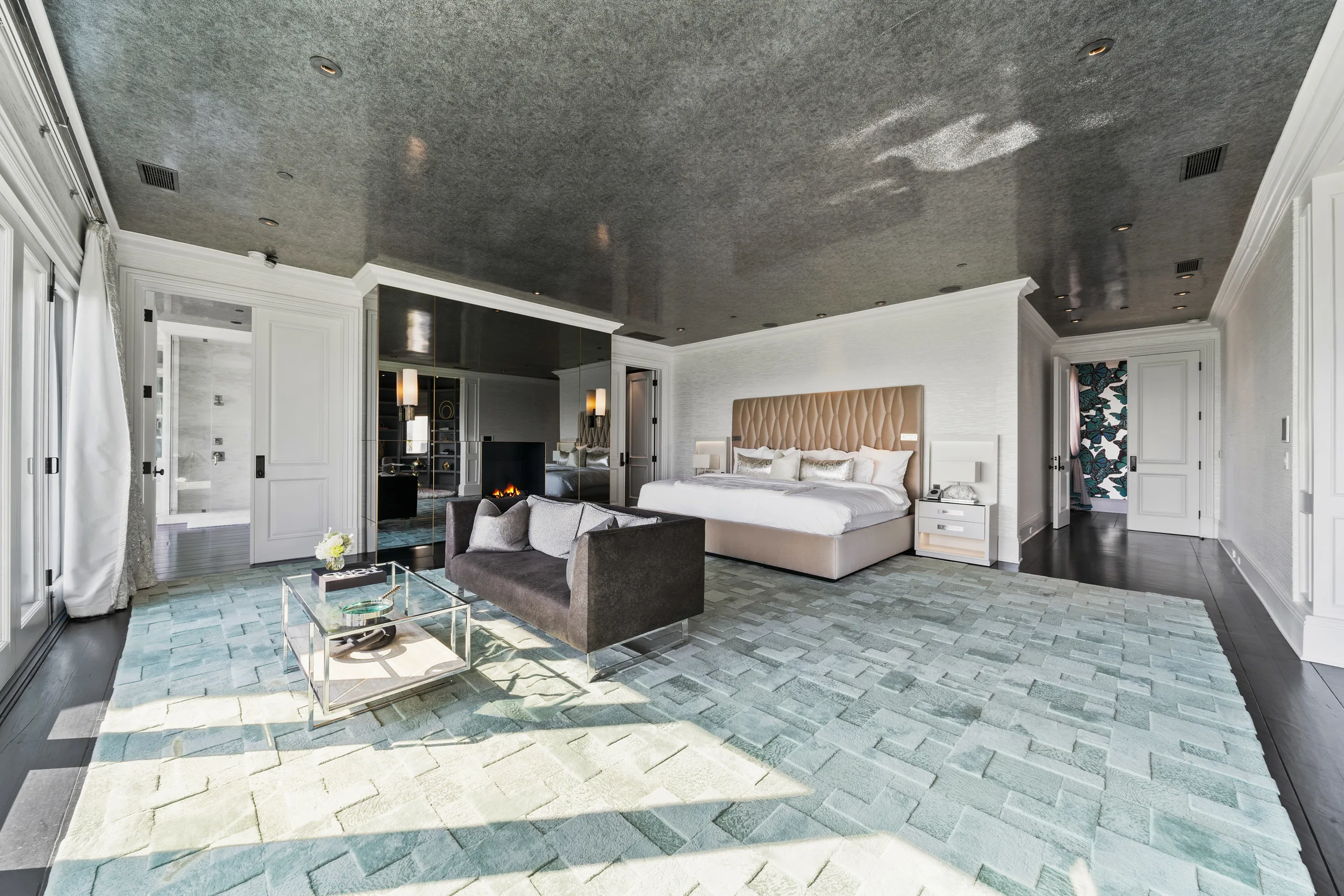 Primary suite with tufted bed, mirrored fireplace wall, loveseat and silvered lacquer ceiling