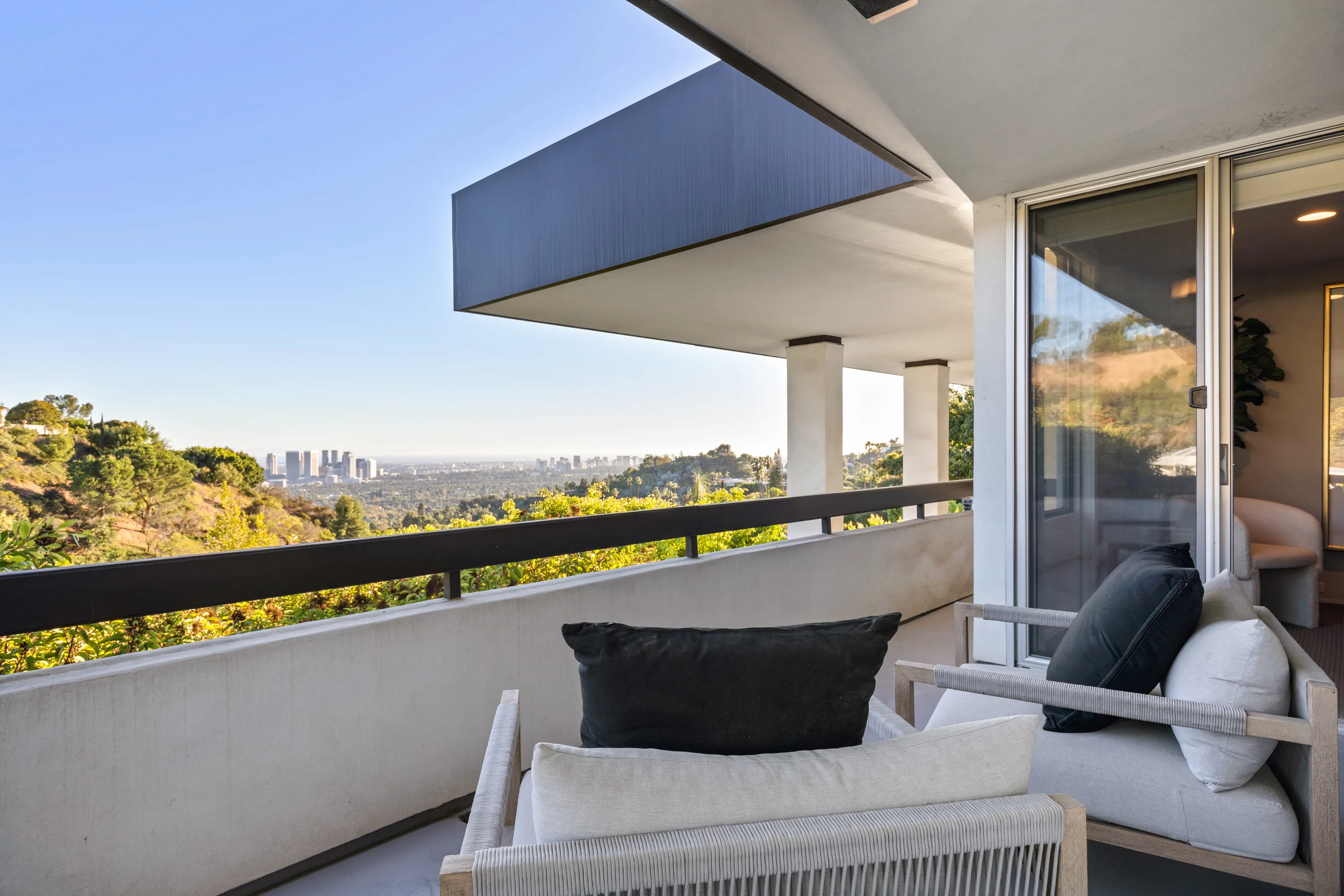 Covered bedroom balcony with rope lounge chairs and a hazy skyline view across the canyon