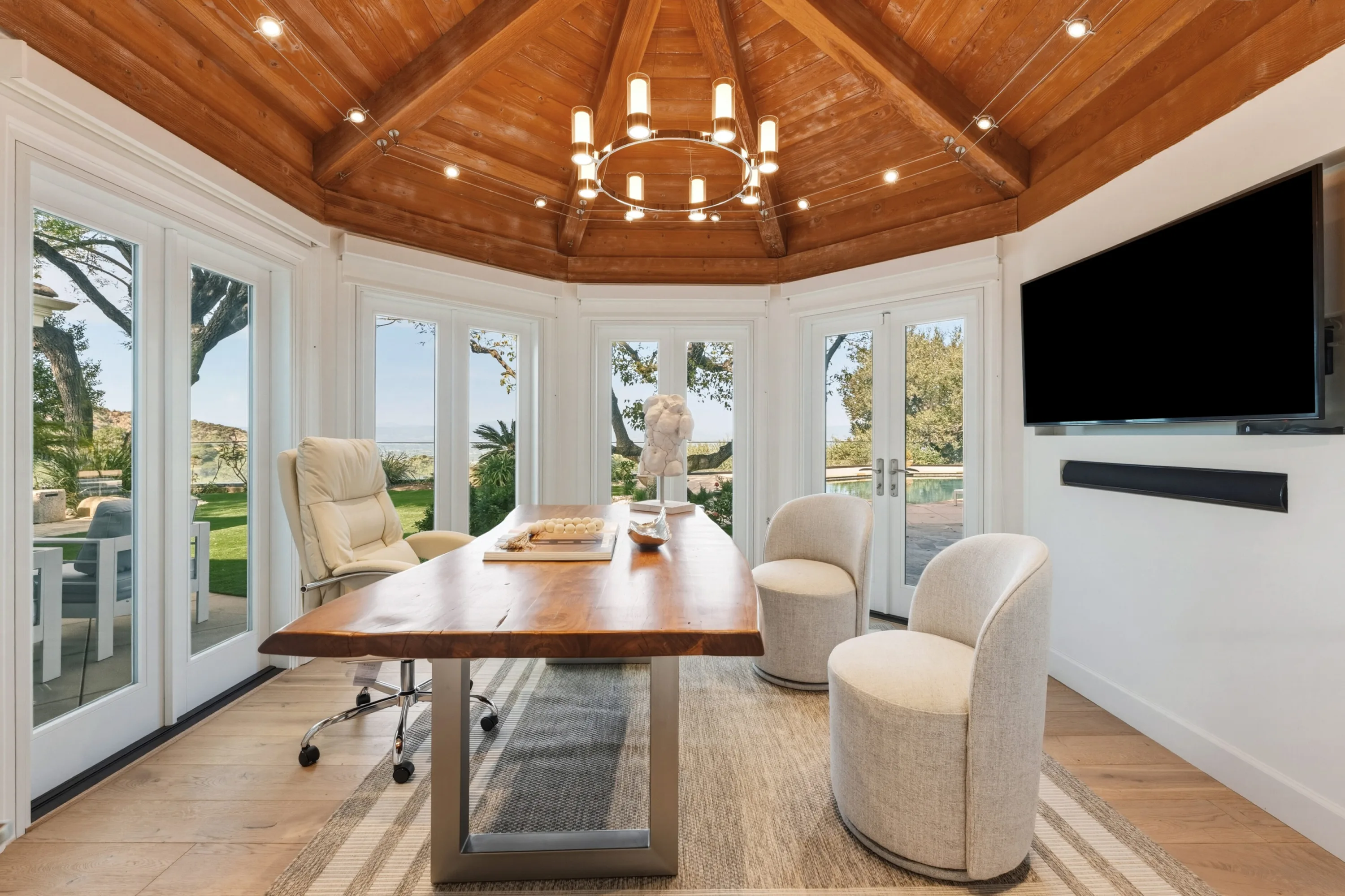 Octagonal study under a cedar-clad ceiling, live-edge desk and French doors to the pool lawn