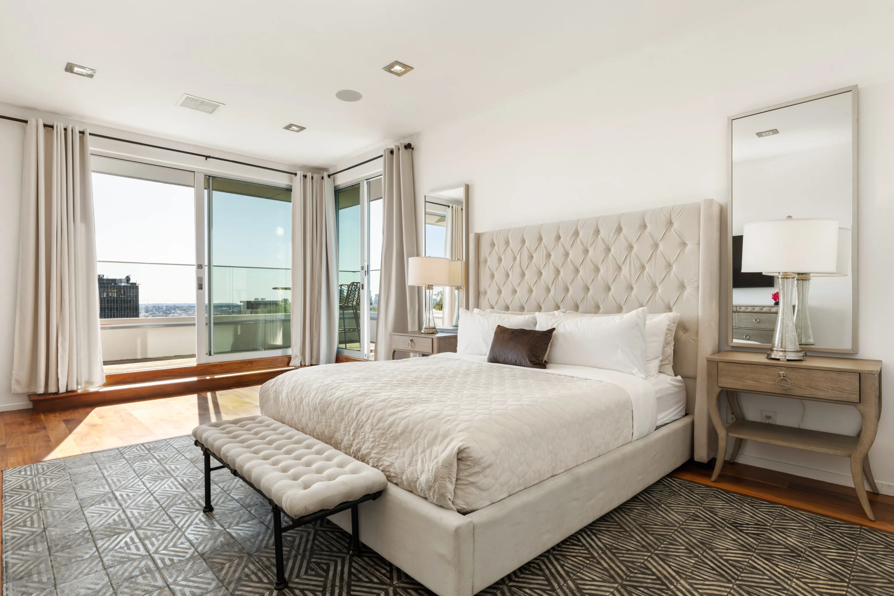 Corner bedroom where sliding doors open to a balcony with skyline views over the hills