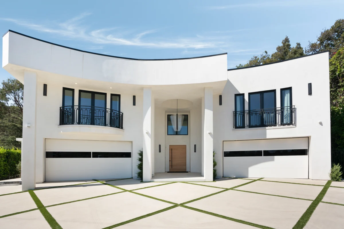 Curved white facade of the Brentwood estate with recessed oak front door and grass-striped motor court