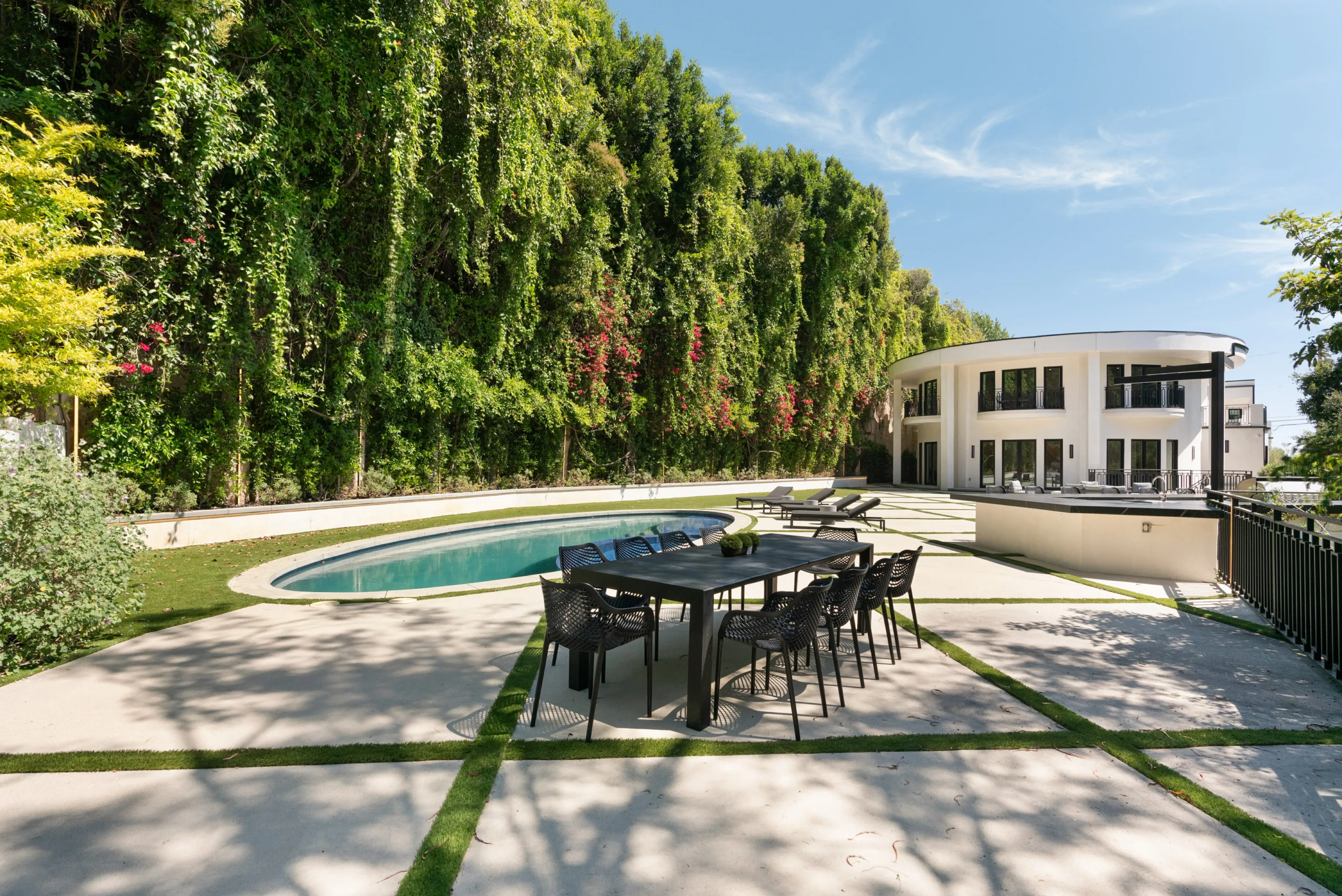 Outdoor dining table for eight on the poolside terrace, with the rounded villa behind
