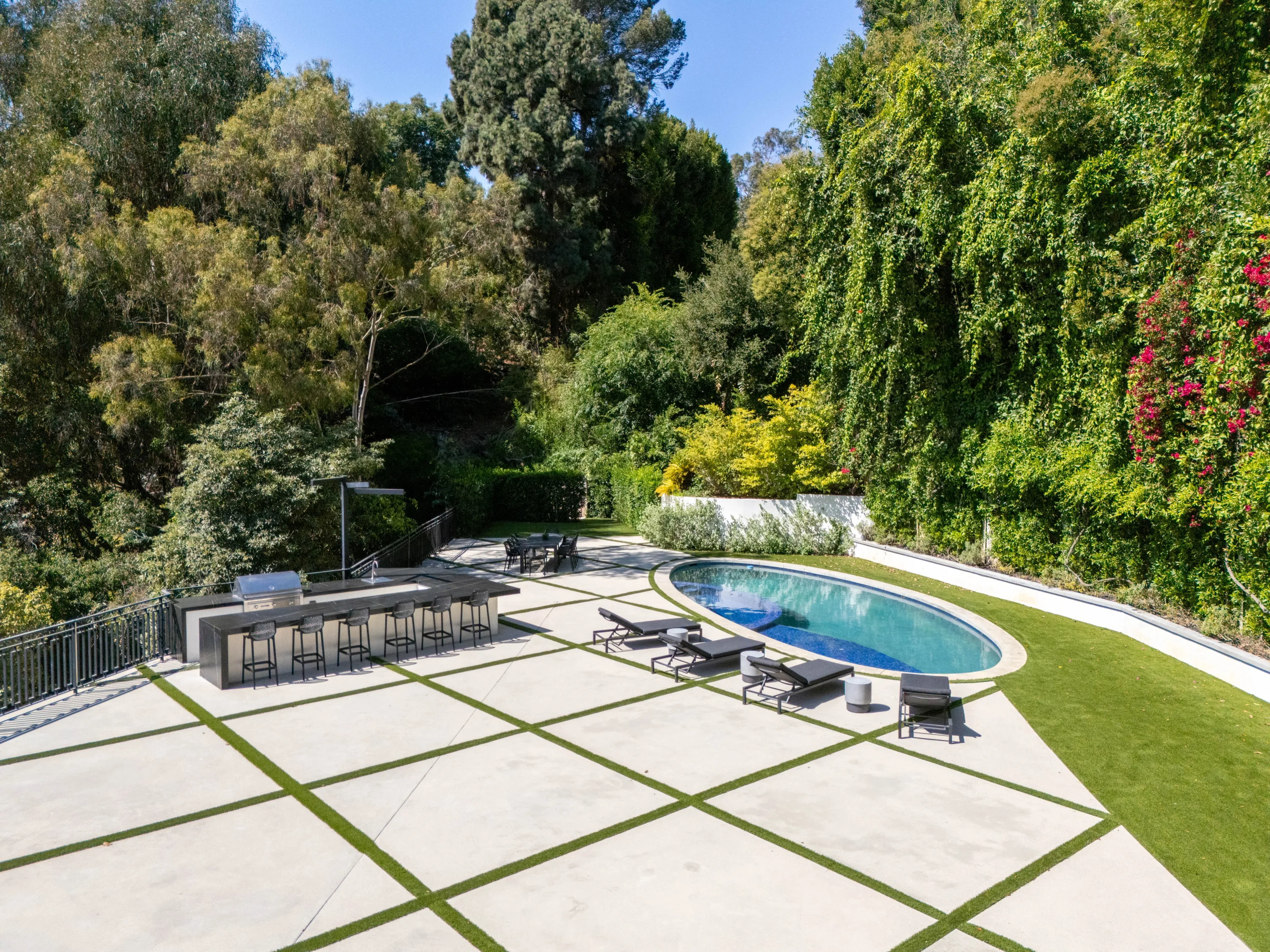 Elevated look across the terrace to the bar, loungers and pool against a hillside of vines