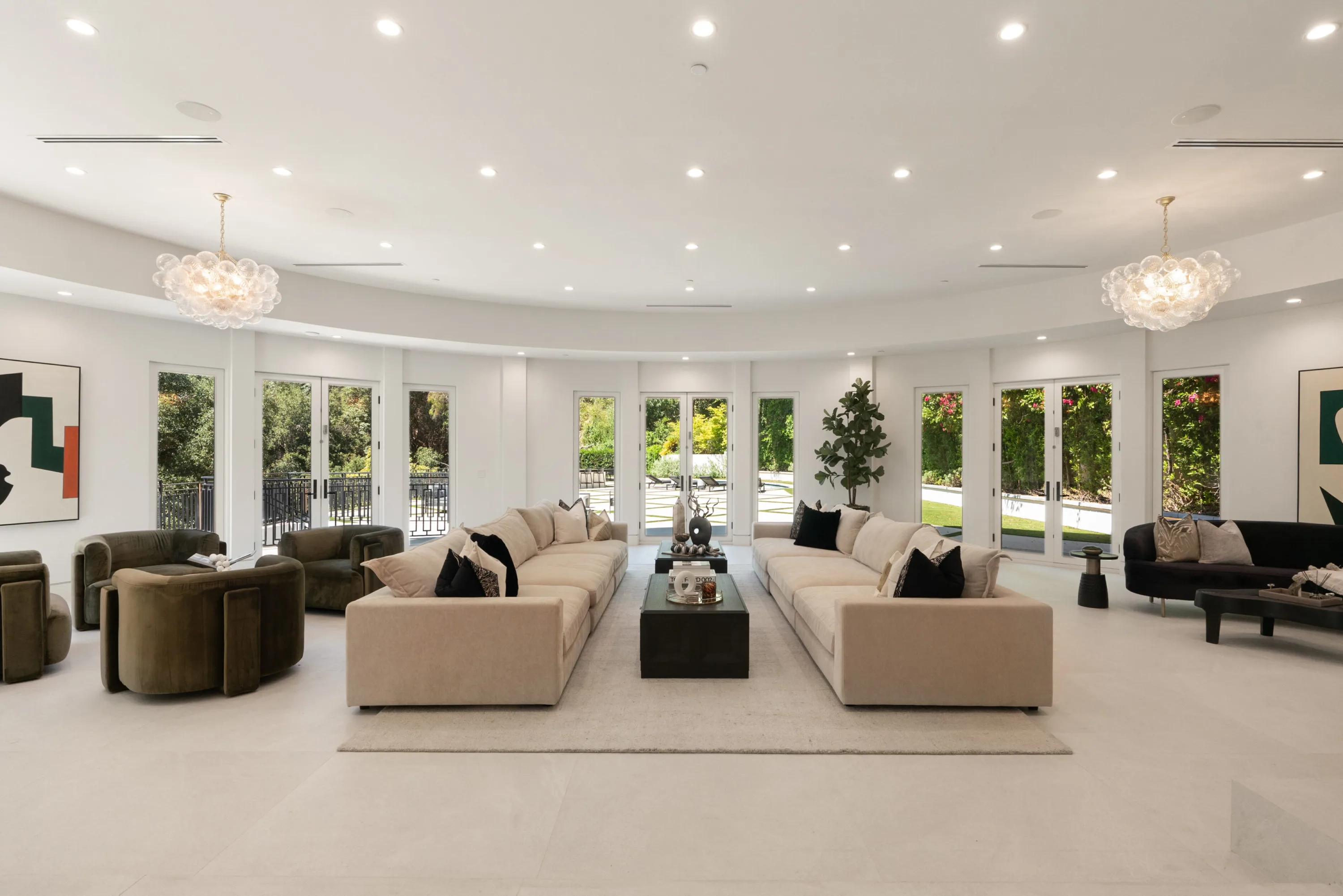 Vast curved living room with facing sofas, bubble-glass chandeliers and French doors onto the garden